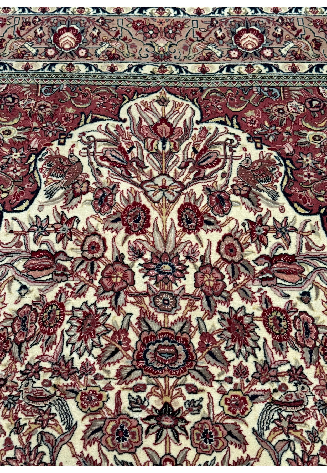 Close view of the rug's corner, displaying the intersection of the borders with the central field, and the meticulous detail of the floral and bird motifs.