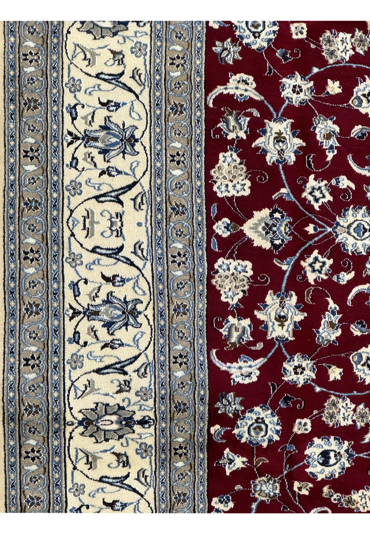Zoomed-in view on the border of the Persian Nain 9La rug, showcasing the detailed craftsmanship of the floral and vine patterns in navy and cream