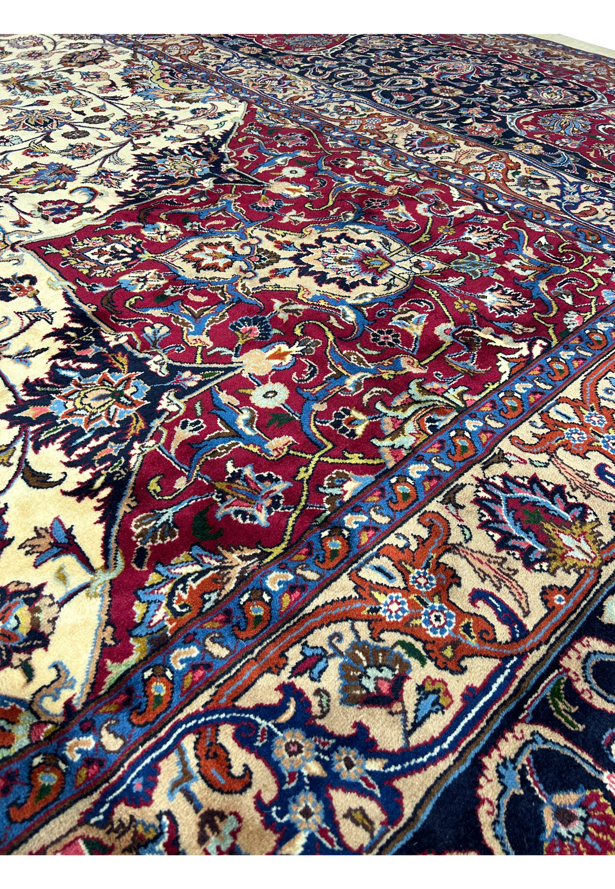 Close-up of intricate patterns and vibrant colors on a Persian Mashad rug, featuring detailed floral and vine motifs in red, blue, ivory, and gold, with exceptional craftsmanship and traditional Persian design elements