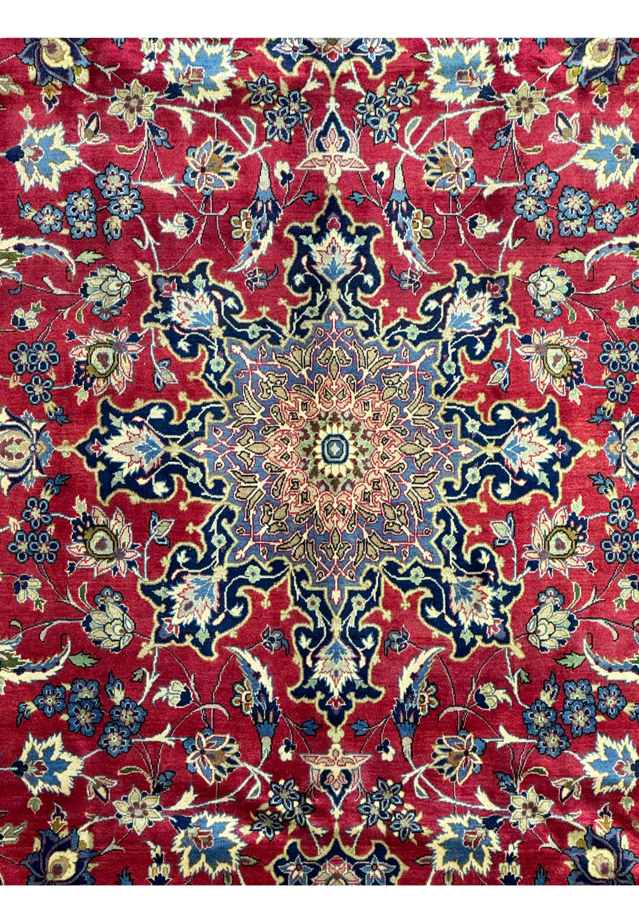 Close up zoomed in on a central medallion of a Isfahan Rug measuring 9'5 x 14'2 emphasizing the deep red and different variations of blues.
