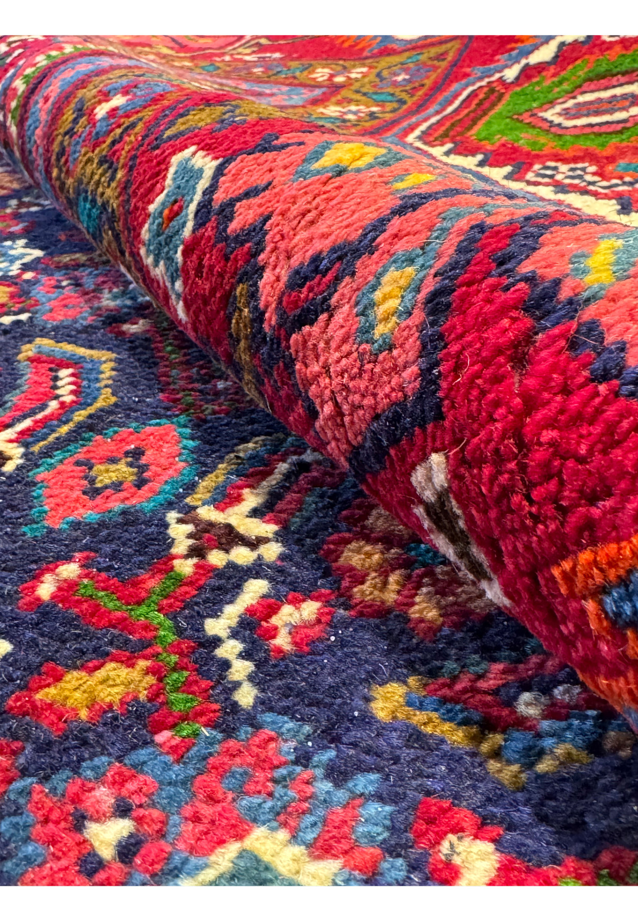Close-up of the edge of a Persian Mahal Rug, showing the fringe and the detailed weave of the border and central field patterns. The intricate geometric and floral designs in rich reds, greens, and blues highlight the meticulous craftsmanship of the rug. This image focuses on the quality of the wool and the precise hand-knotting, reflecting the luxurious feel and the artistic tradition of Persian Mahal rugs.