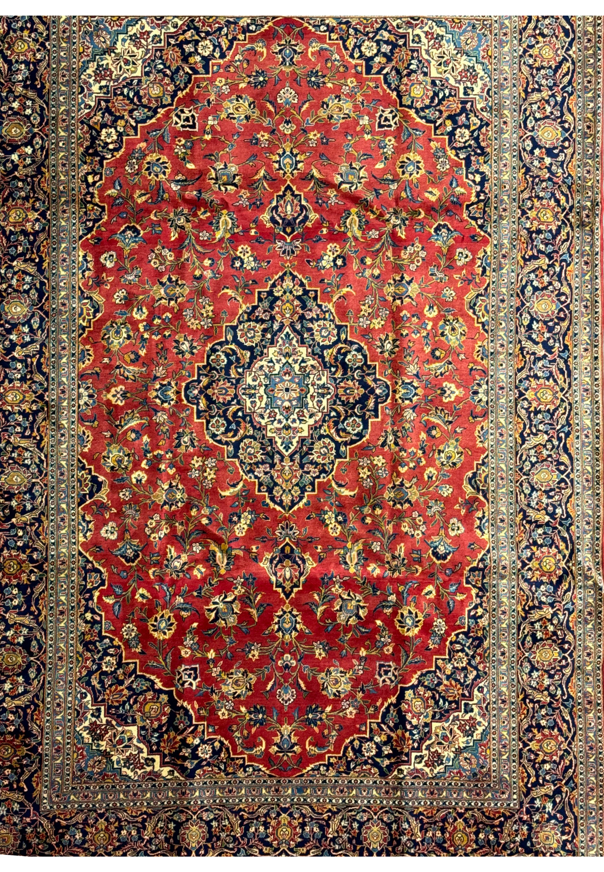 Detailed shot of the central medallion on a Persian Kashan rug. The medallion features a complex design with layers of floral motifs and geometric shapes in shades of blue, gold, and ivory against a red field. The precision of the knotting and the clarity of the design highlight the skill involved in creating this luxurious rug. This close-up emphasizes the artistic quality and cultural heritage embedded in Kashan rugs.