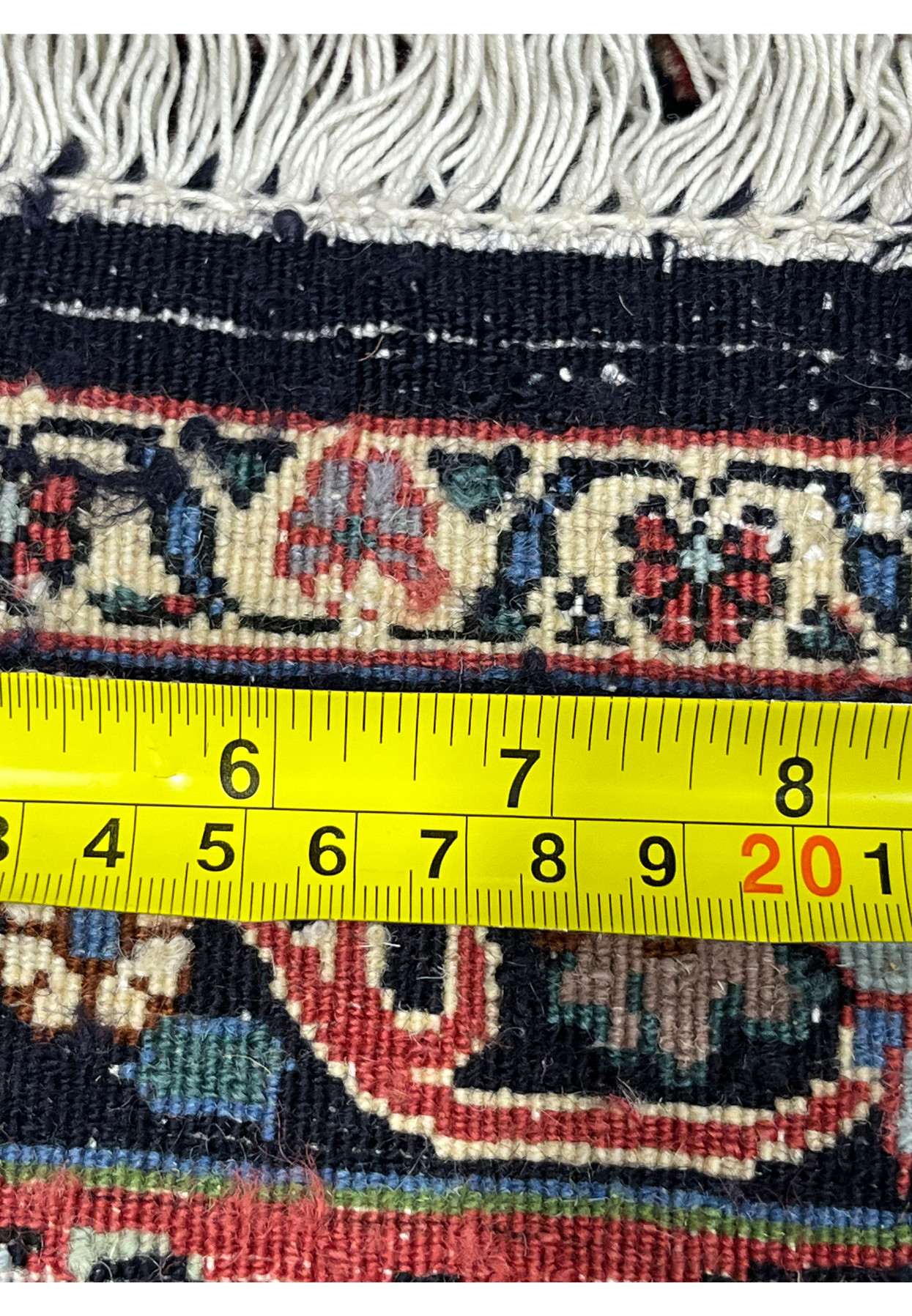 Backside view of a Persian Bijar rug measured with a ruler, showing tight symmetrical knots, heavy wool foundation, and precise hand-knotted craftsmanship.