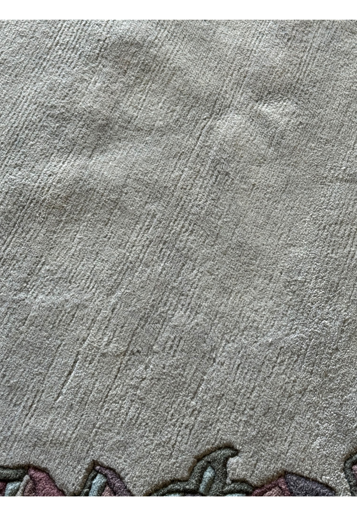 Close-up of the midfield of the modern Nepal rug, showcasing a subtle, textured surface in a light gray shade with minimal patterning.
