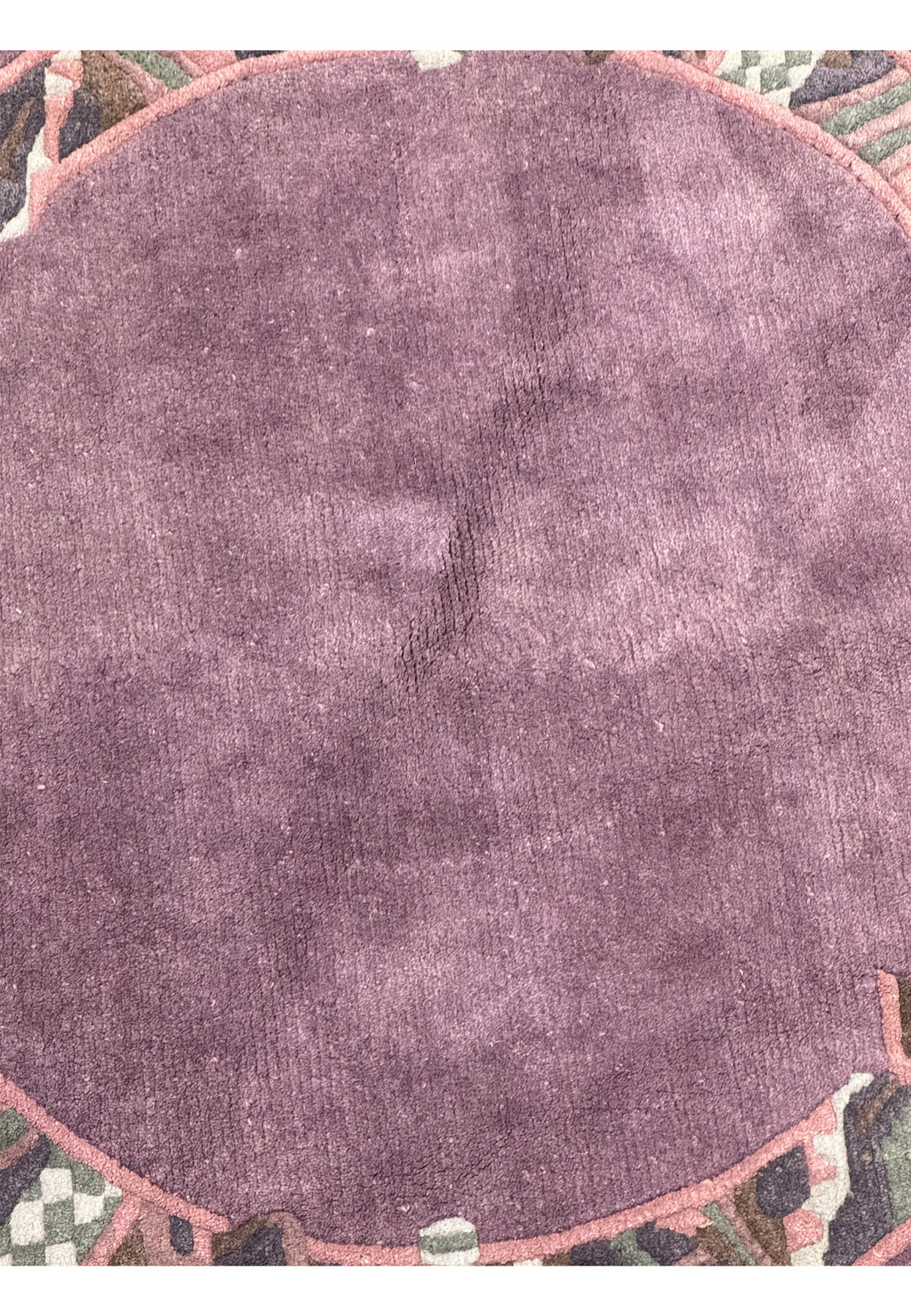 Close-up of the rich plum center field of the 4'8 x 4'8 round Nepalese rug, showing fine wool texture.