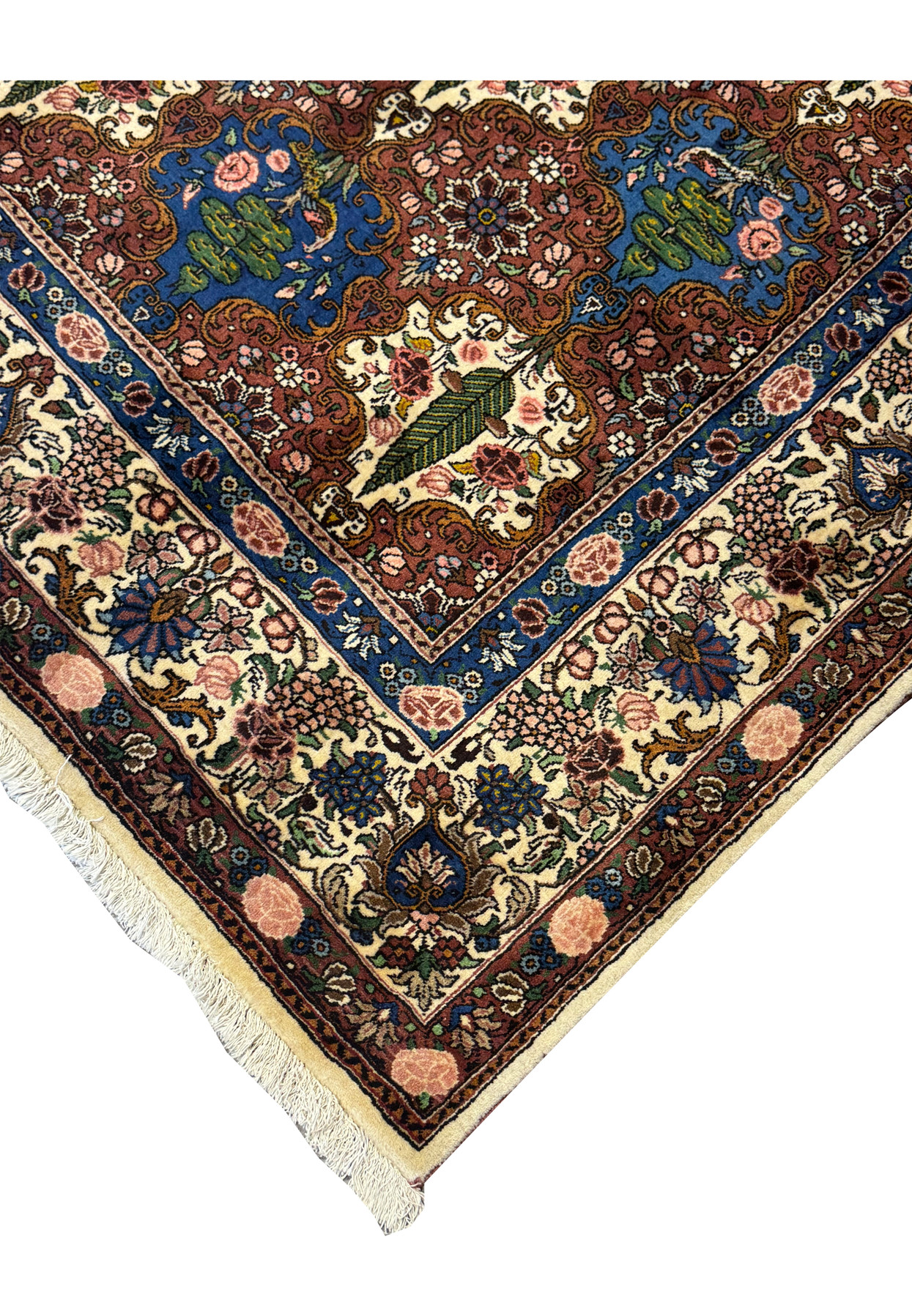 Edge of a Persian Bakhtiar Rug with floral motifs and the signature of the master weaver on the corner.