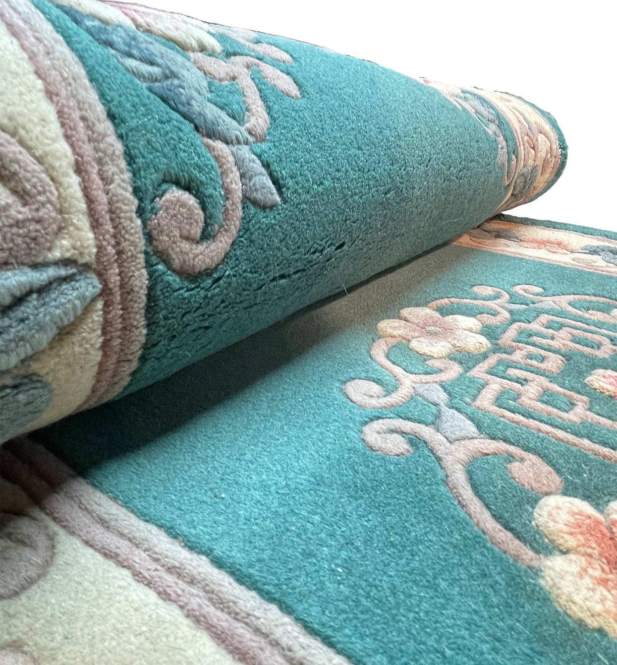 Walter Nichols Art Deco Runner rolled to display its wool pile and floral patterns in teal.