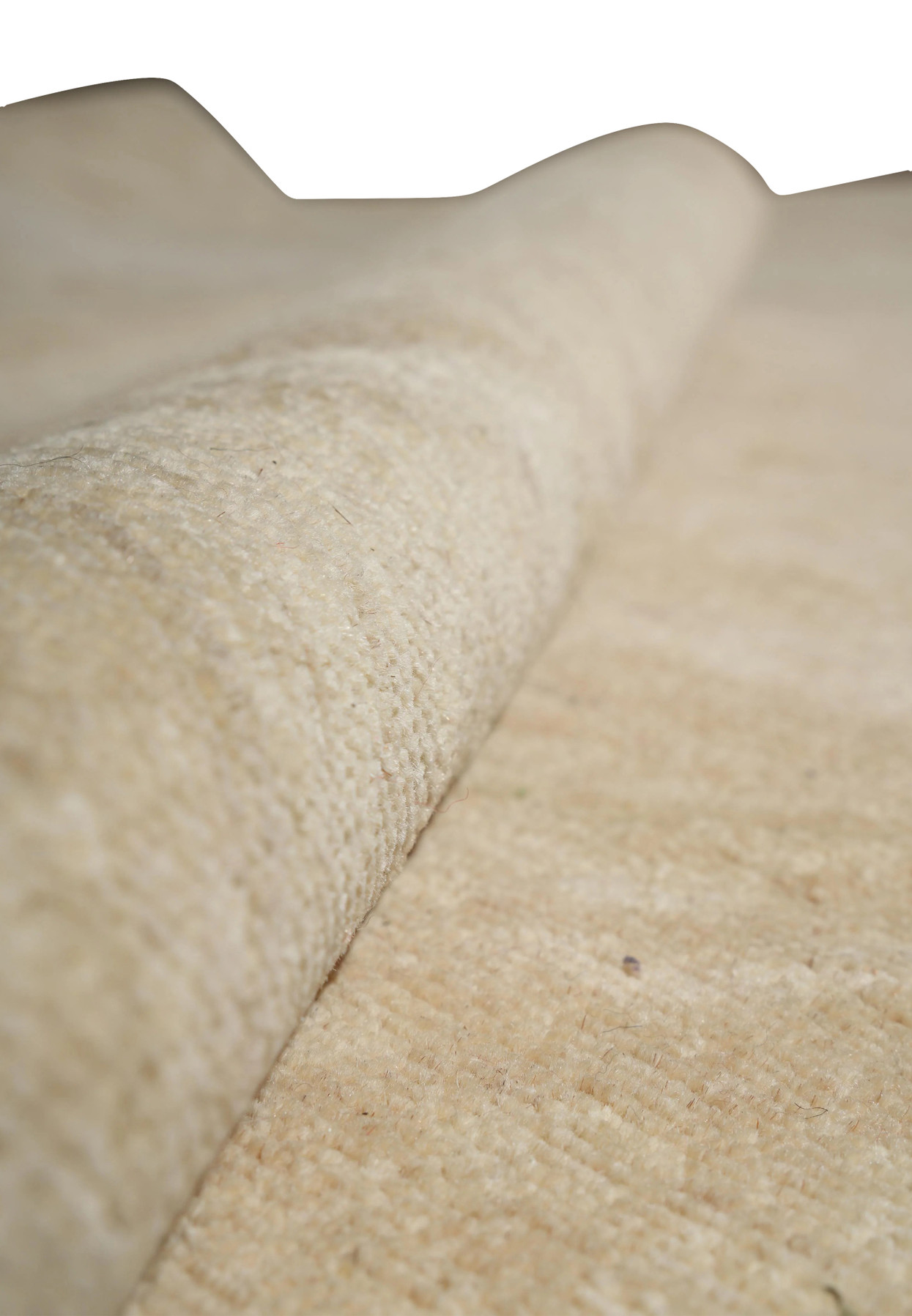 Side angle of rolled Chobi wool rug showing thick natural pile and texture in muted neutral tones.