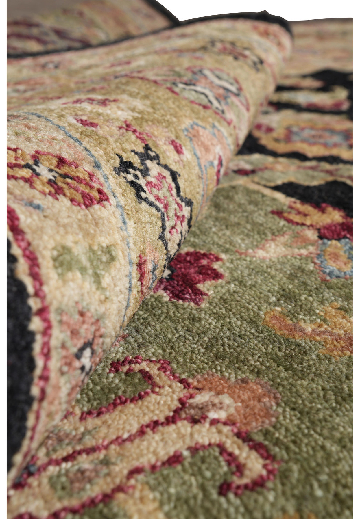 Rolled edge detail of Oushak rug showing plush wool texture and multicolor floral patterns in red, gold, and olive tones.