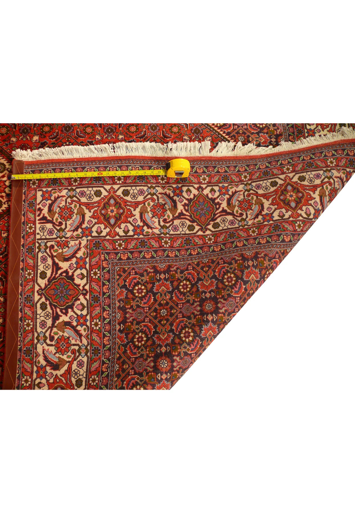 Back of Bijar rug folded to show fine knots, sturdy selvage, and tape measure for scale.