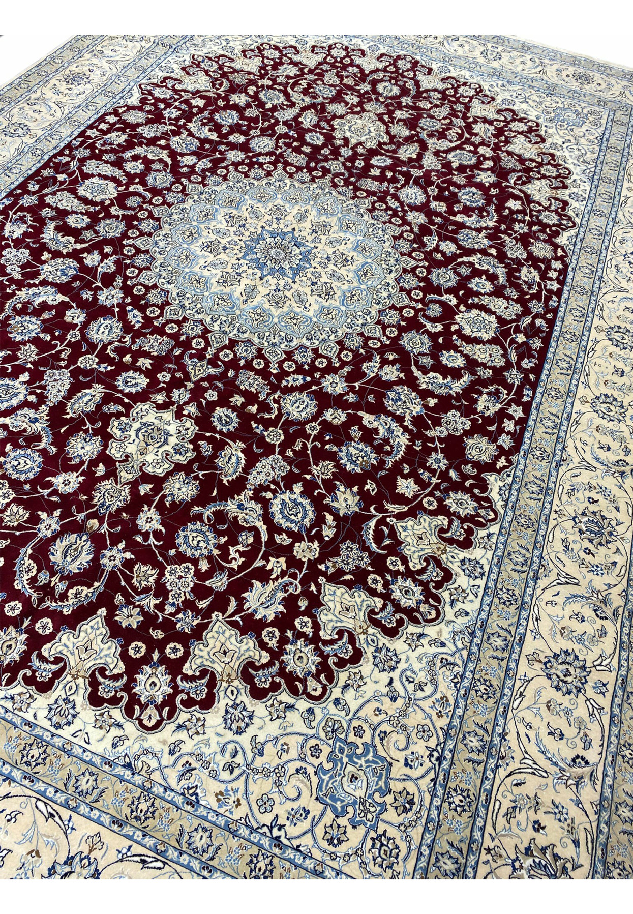 Large palace-size red Persian Nain 9 LAA rug shown at an angle with ivory floral borders