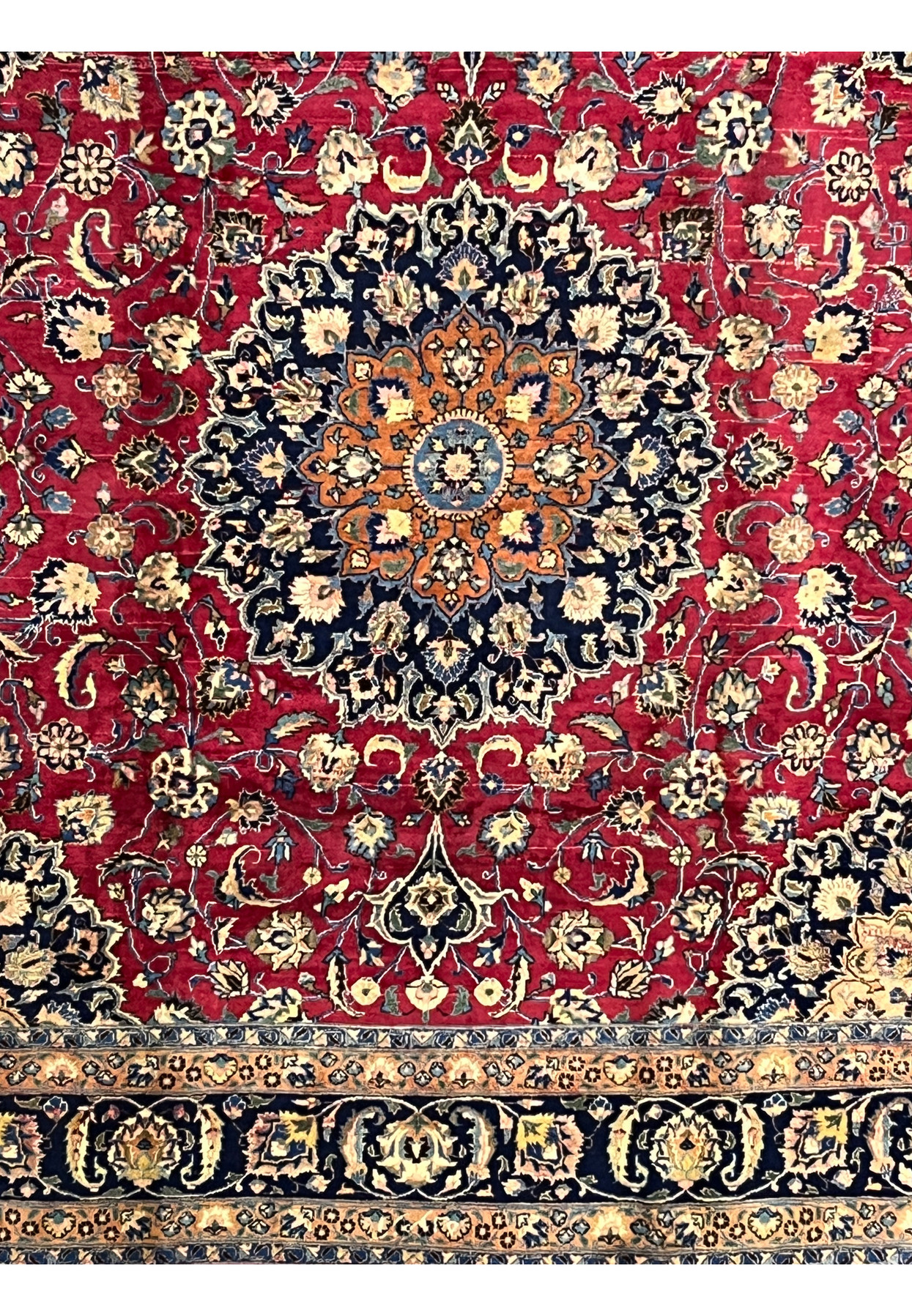 Midfield view of Mashad Rug featuring navy and gold medallion surrounded by red floral design