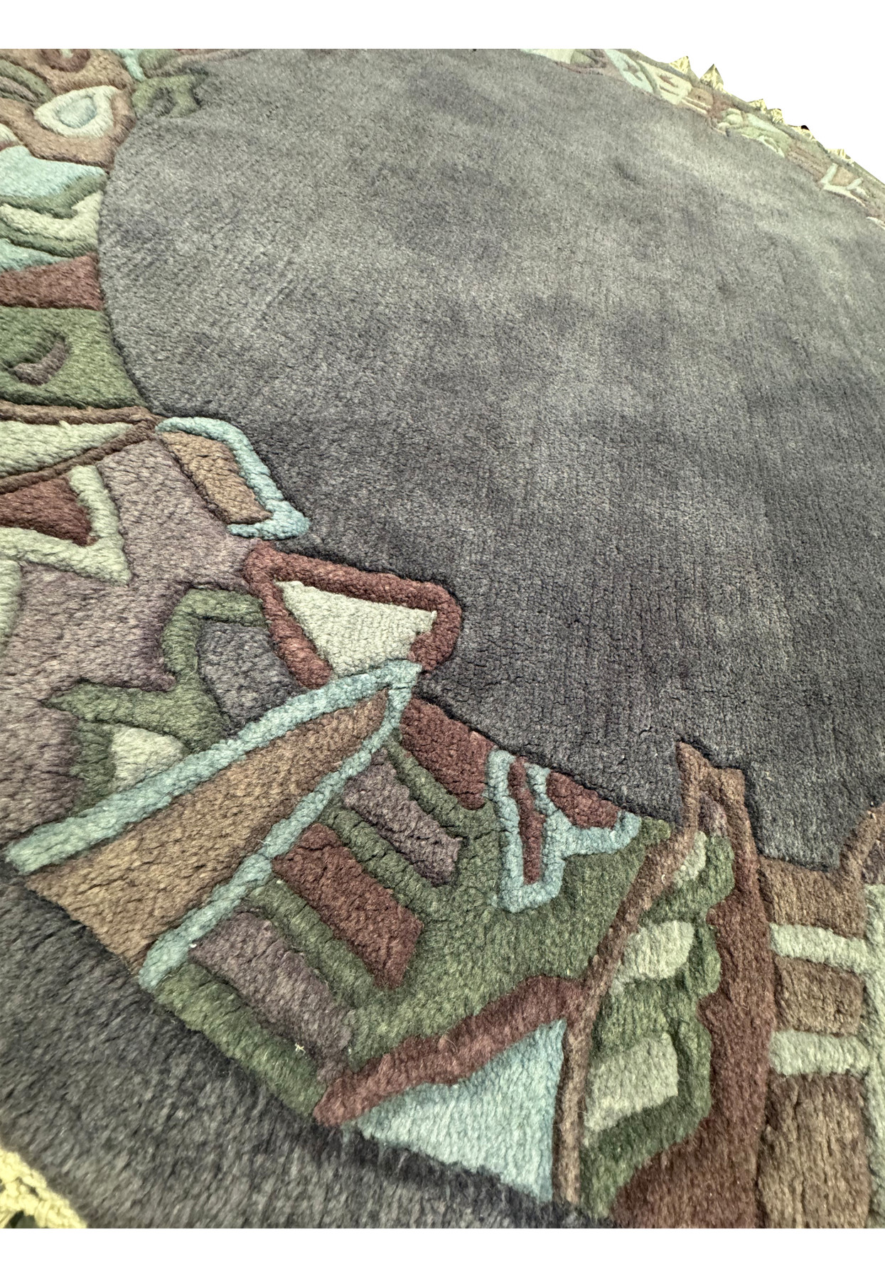 Angled perspective of the round 5'3 x 5'3 Nepal rug illustrating the dimensional relief of its border and the soft sheen of its charcoal wool center.