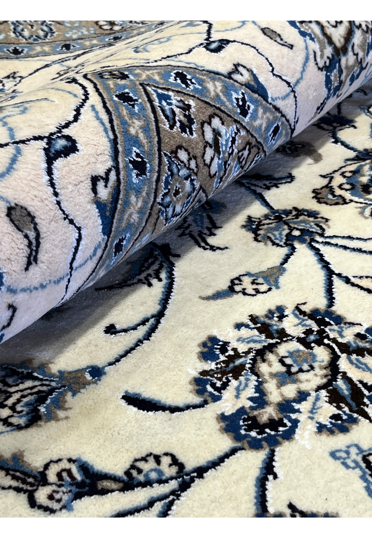 Rolled 10x13 Persian Nain 9LA Rug highlighting ivory and blue field with silk shimmer and fine floral detailing.
