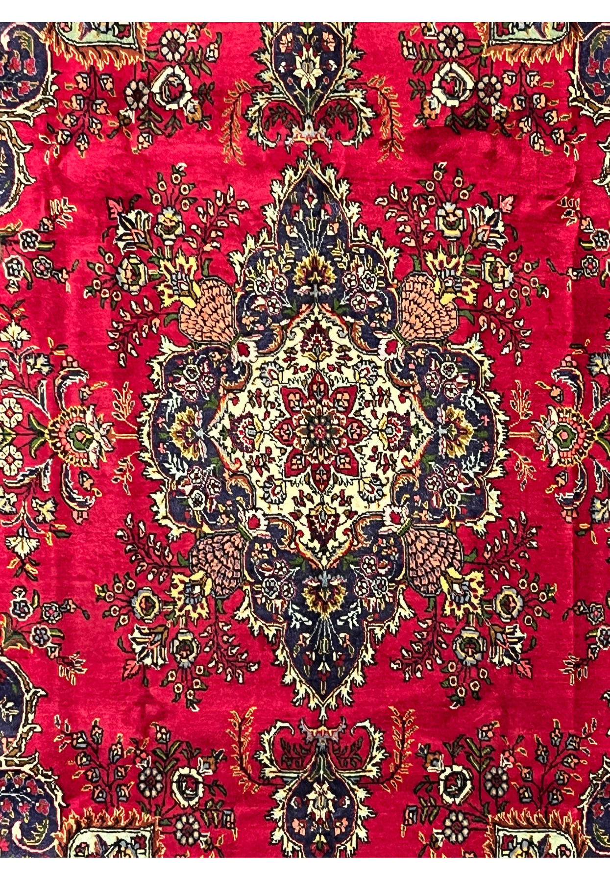 Close-up of central ivory medallion with floral motifs on red background of Persian Tabriz wool rug