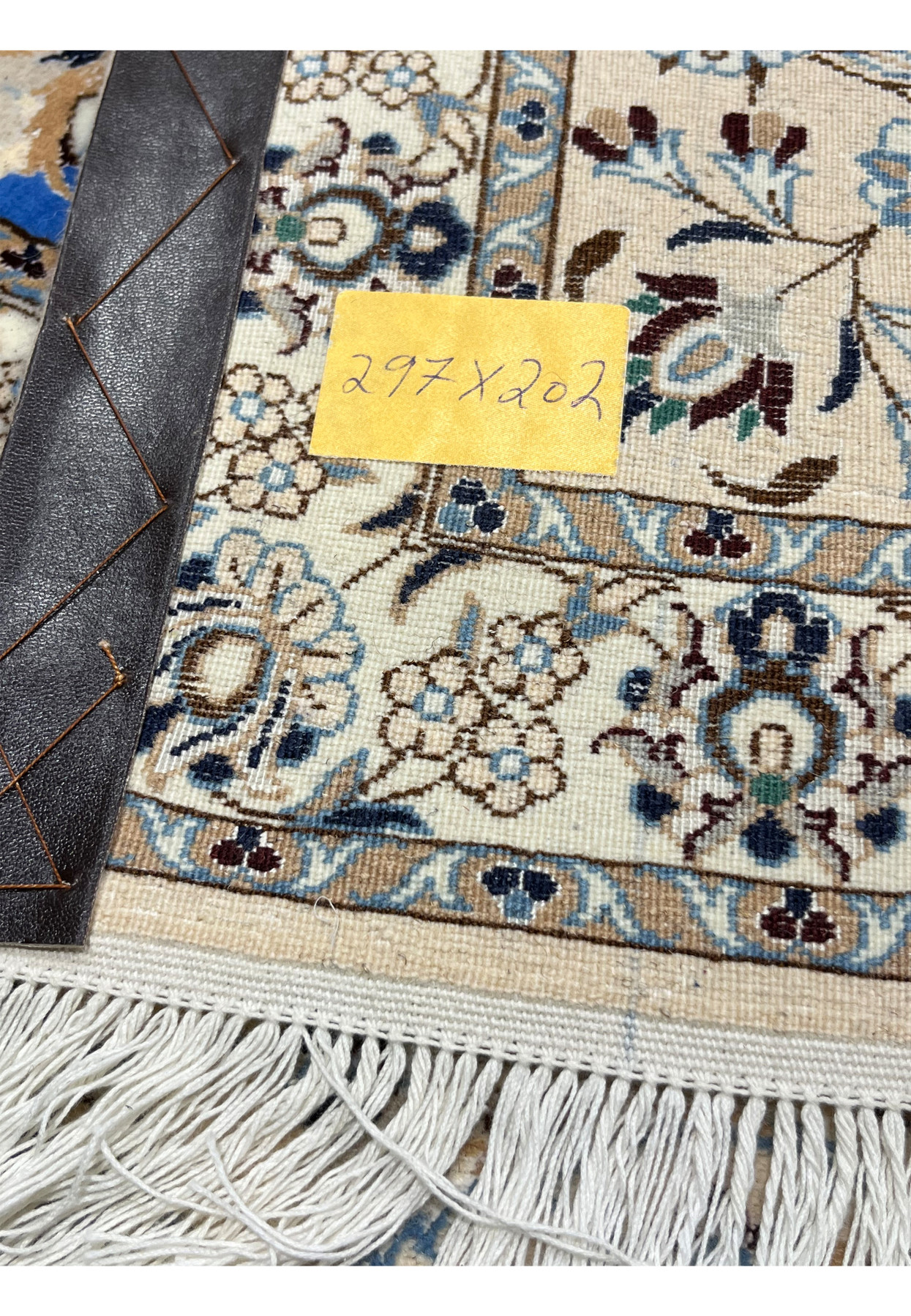 Backside view of Persian Nain 6 LA hand-knotted rug showing detailed knot structure, ivory base tones, and evenly woven blue and beige floral motifs.