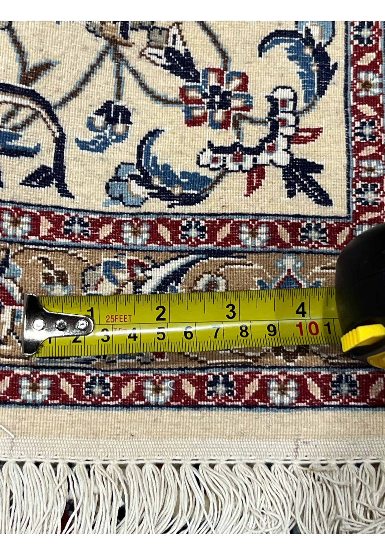 Closeup of measuring tape on backside of Persian Nain 4 LA Habibian rug showing knot density and precise weaving on natural wool warp and weft.