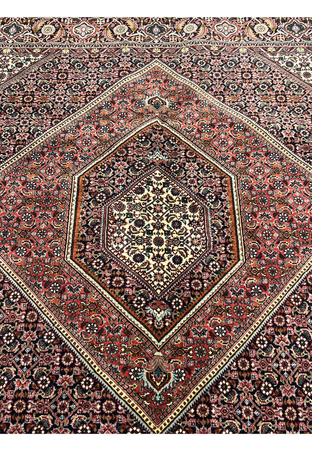 Detailed shot of the central medallion of Bijar Persian rug showing symmetrical floral motifs in ivory, rust, and navy with fine lattice outlines.