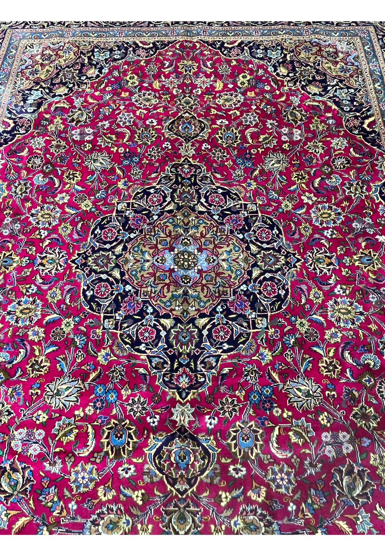 Close-up of medallion on Mashad rug featuring navy, ivory, and light blue floral layers.