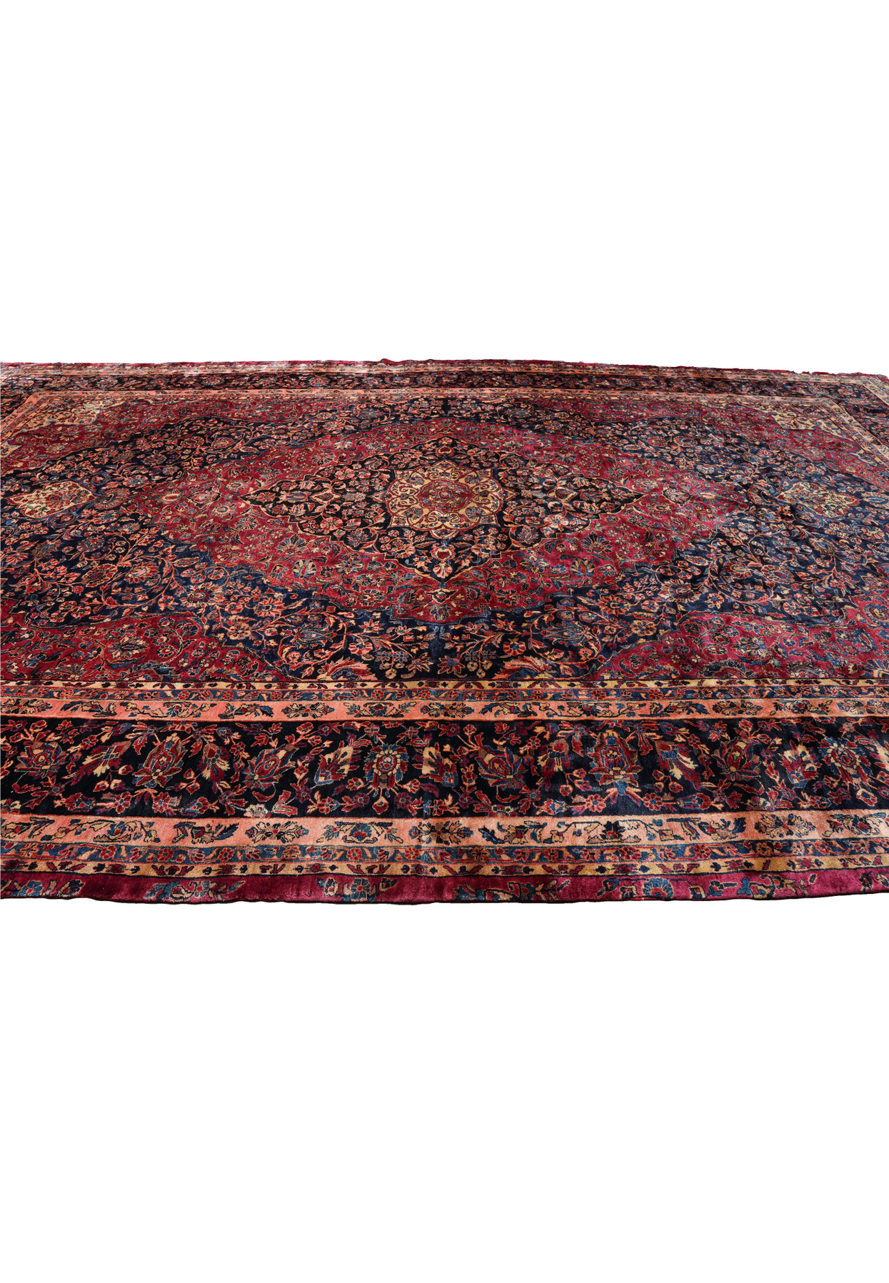 Side perspective of antique Persian Kashan rug displaying large scale, floral medallion, and intricate border work in navy and red.