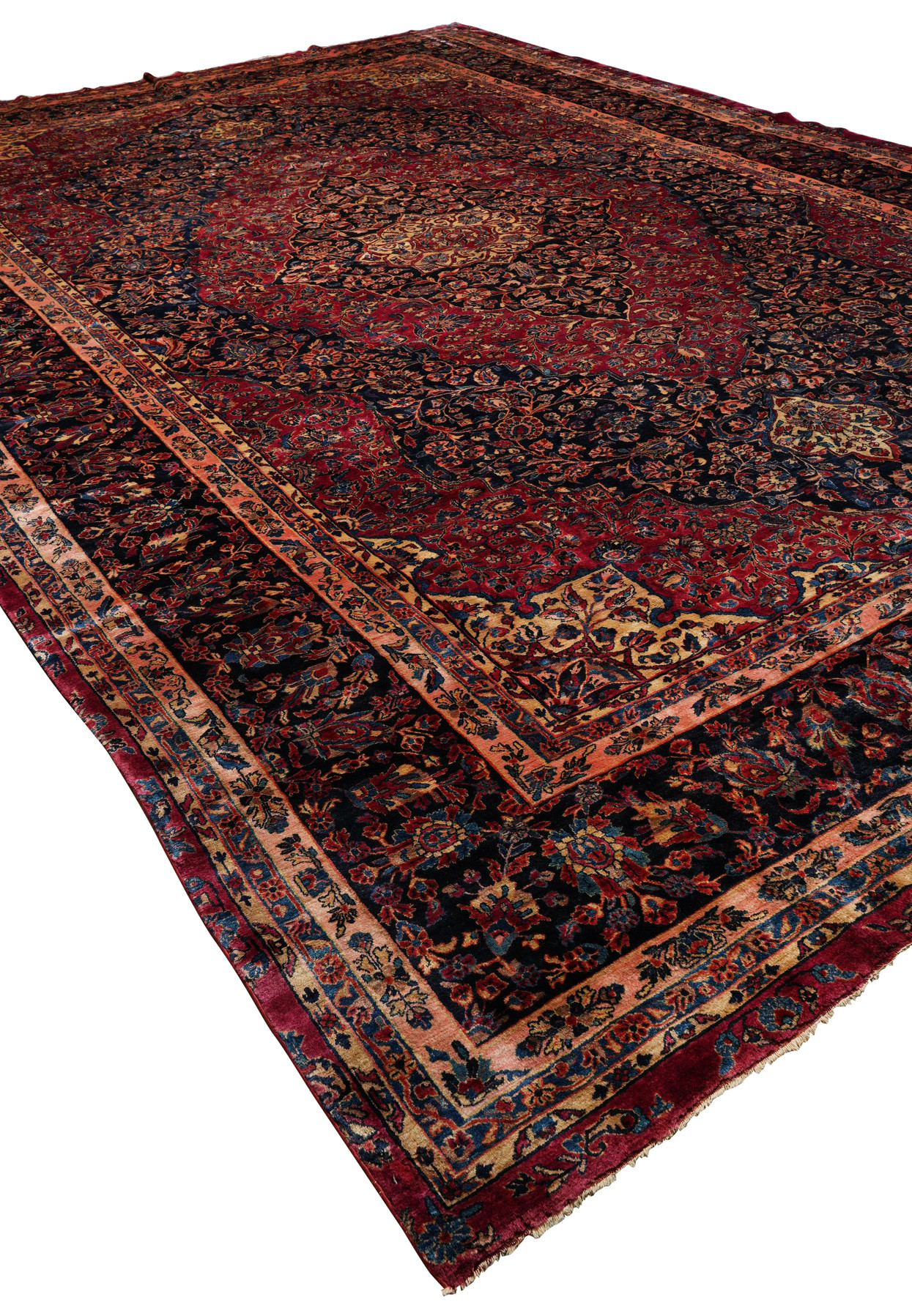 Angled view of 12'7 x 19'5 antique Kashan rug showing sheen of soft wool, deep red field, and detailed navy floral borders.