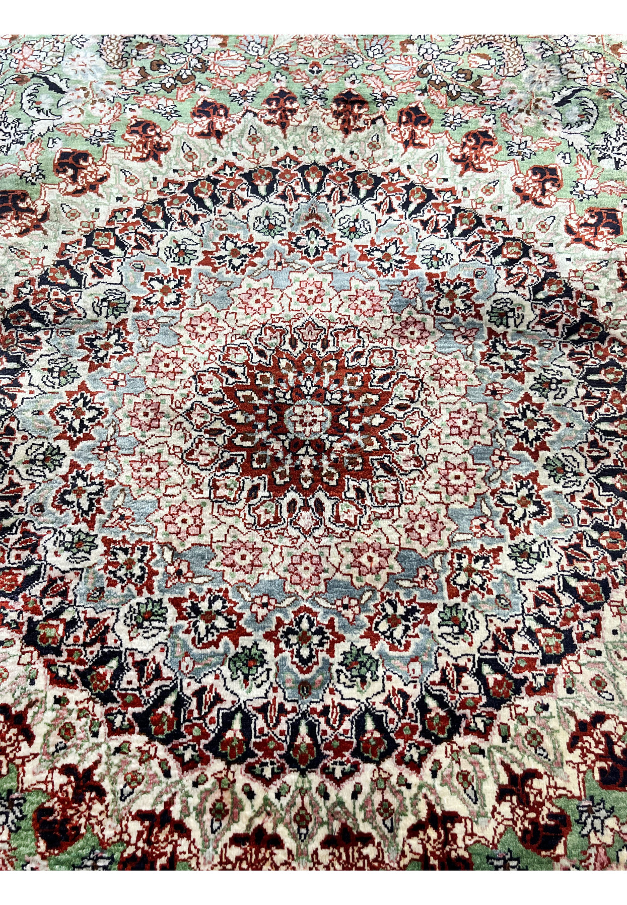 Close-up of the Qum pure silk rug medallion with detailed red, blue, and ivory floral patterns woven at approximately 600 KPSI.