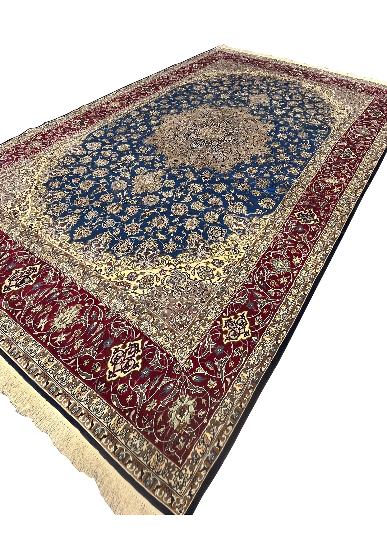 Angled perspective highlighting the shimmer of wool and silk across the blue field, medallion, and red borders.