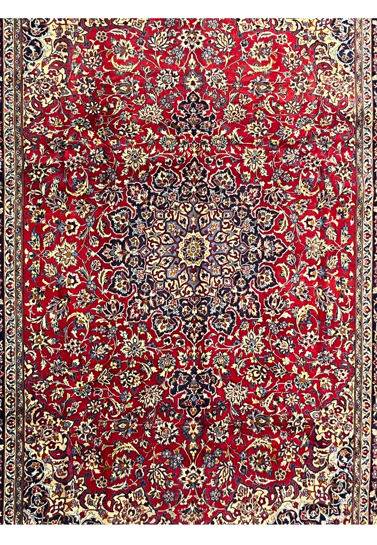 Close-up of Persian Isfahan rug medallion with navy, ivory, and blue floral detailing on a ruby red background
