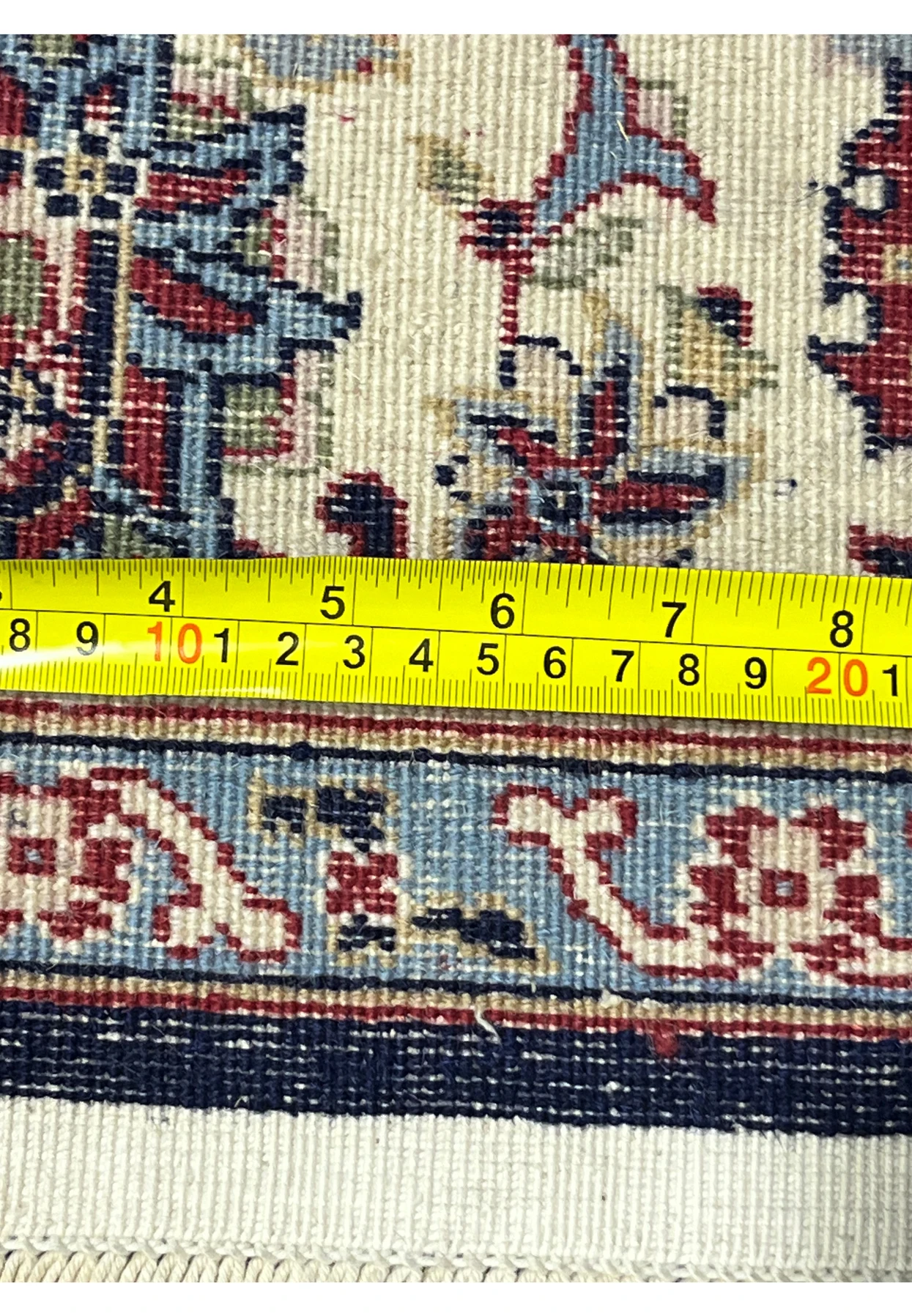 Backside of a navy blue Persian Sarough kork rug with measuring ruler showing precise weave density and straight selvedge alignment