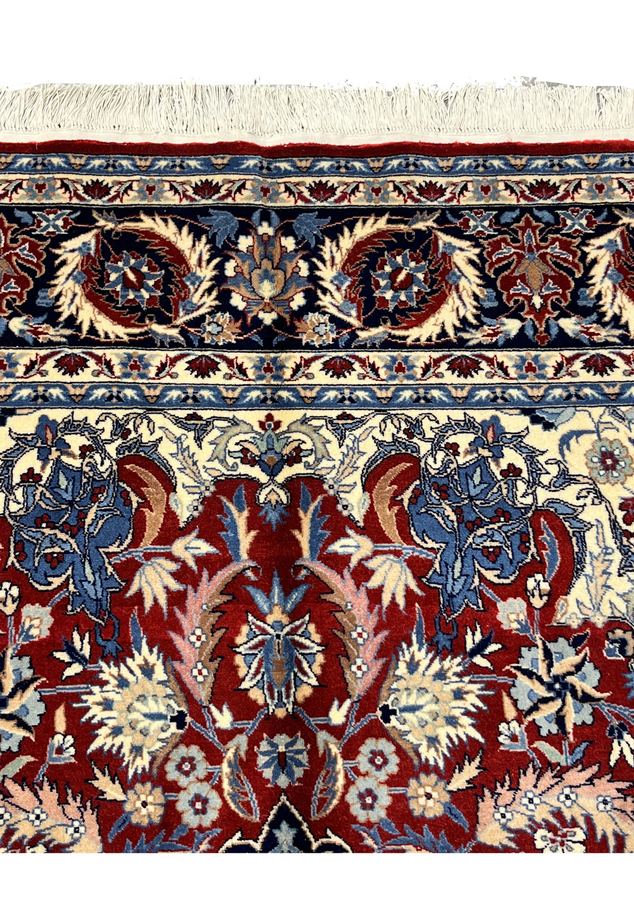 Upper end border detail of Persian Tabriz rug with navy floral border band, ivory accents, and fringe at the top