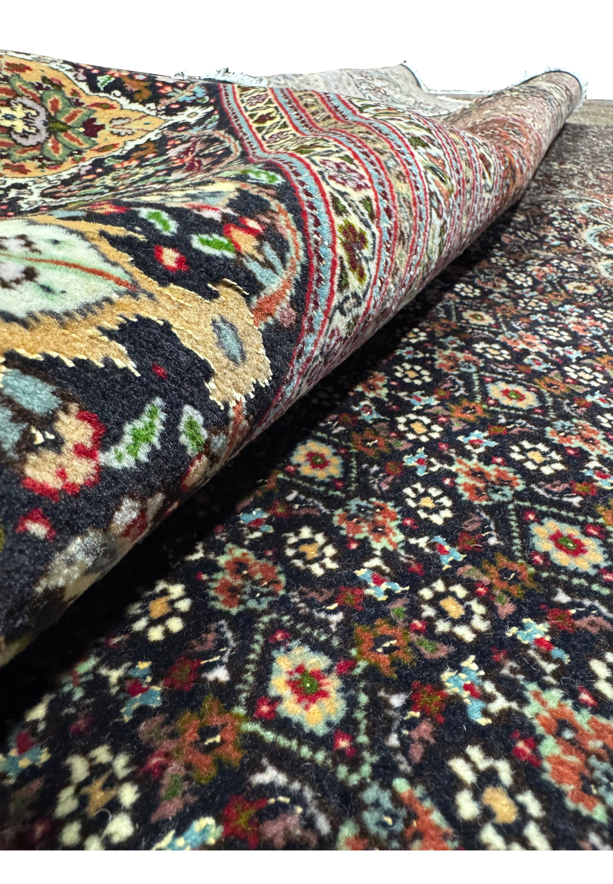 Angled rolled view of an 11.5 x 16.5 Persian Tabriz Mahi 50 Raj rug revealing dense pile, flexible structure, high knot count, and richly detailed floral fish pattern surface