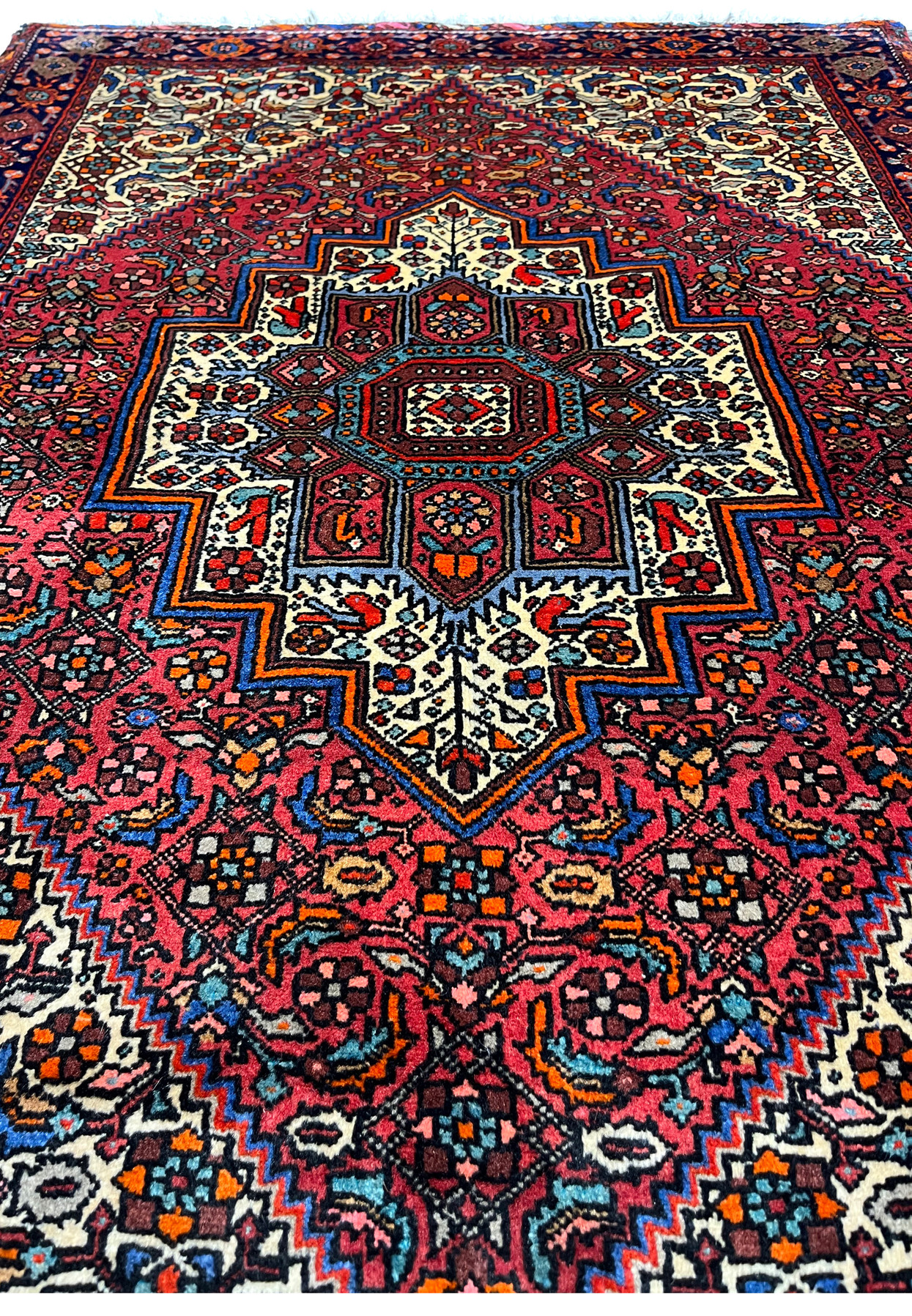 Midfield view of a Persian Gholtogh rug highlighting repeating geometric elements, balanced spacing, red ground, and crisp ivory and blue detailing