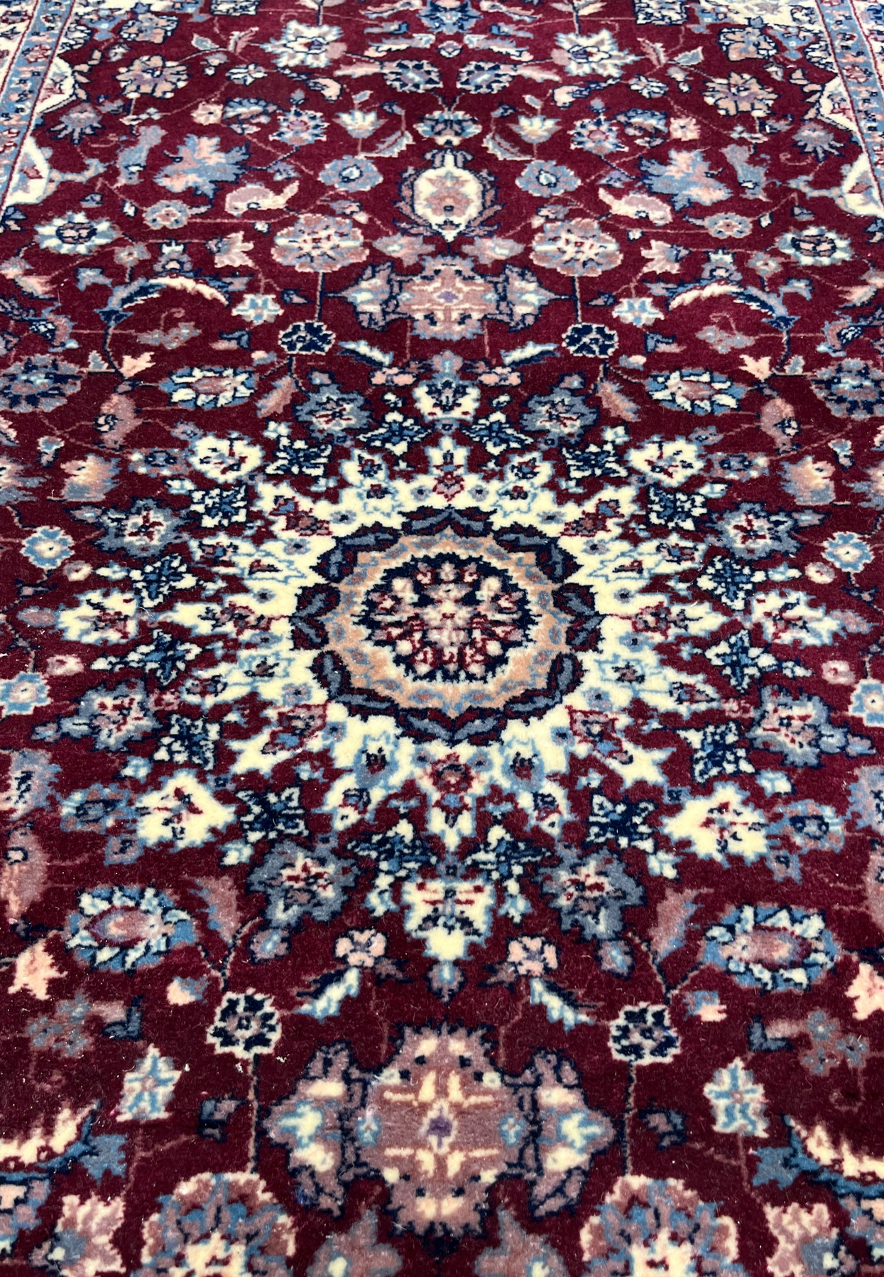 Detailed close-up of the medallion in a Persian Tabriz rug showing precise knot structure, ivory highlights, navy outlines, and refined floral geometry