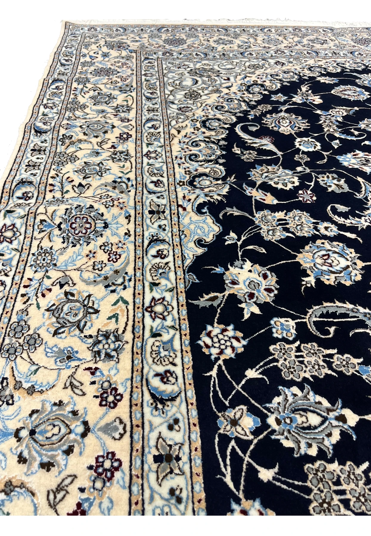 Angled side view of a 7x10 Persian Nain 6LA rug showing low, refined pile, crisp pattern definition, and elegant contrast between navy field and ivory border