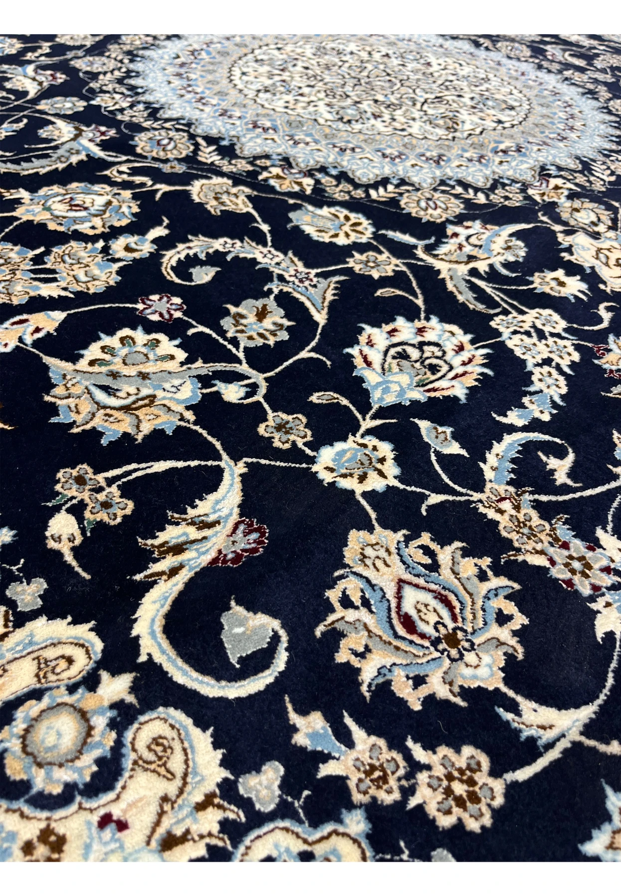 Close-up of a 7x10 Persian Nain 6LA Habibian rug showing deep navy field with delicate floral vines in ivory, light blue, beige, and soft brown wool