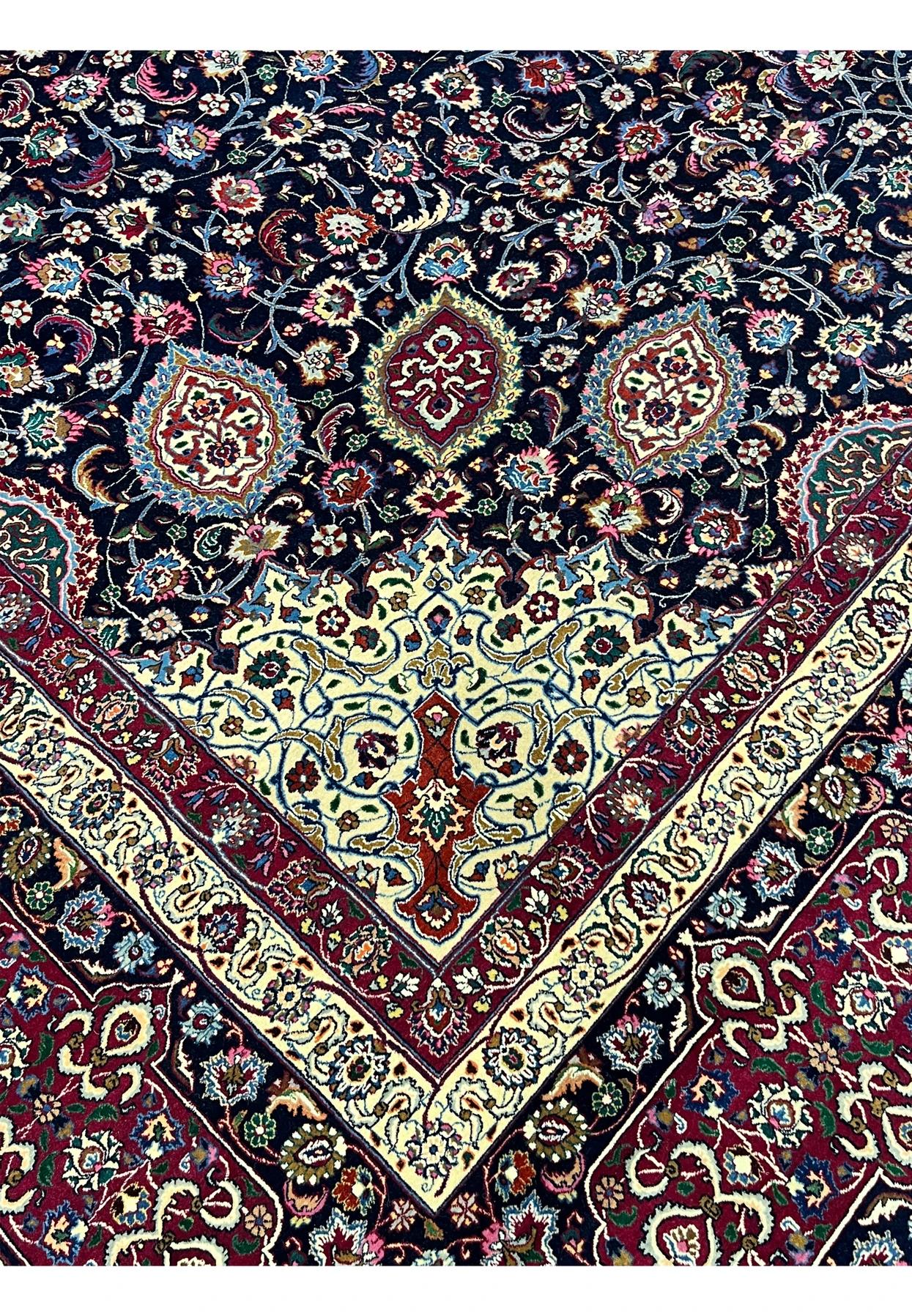 Inner border closeup of Persian Mashad rug highlighting delicate floral scrolls, precise knot work, silk highlights, and harmonious color balance.