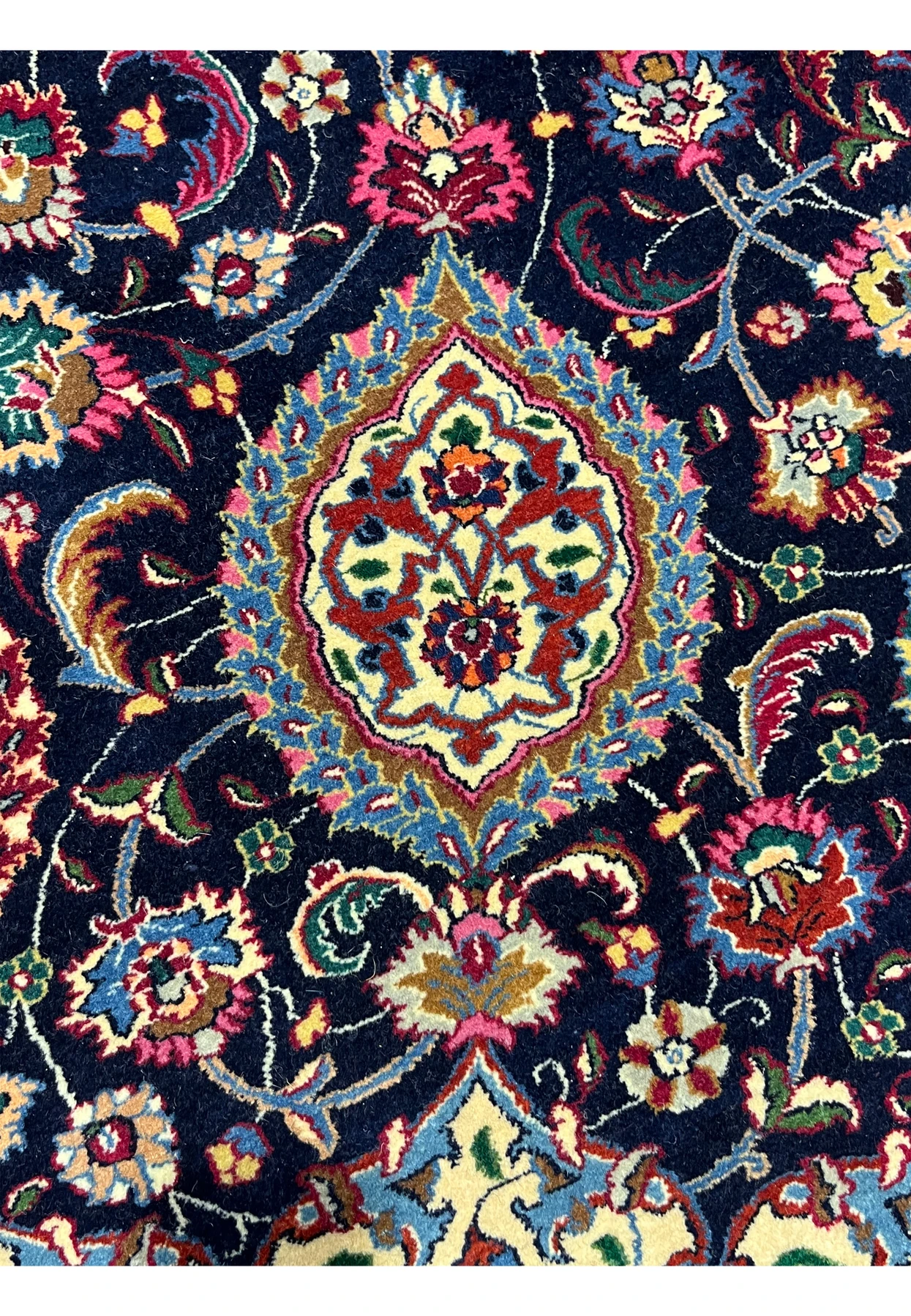 Detailed Persian Mashad rug motif featuring floral medallion elements, intricate curvilinear vines, and silk highlights on a deep navy background