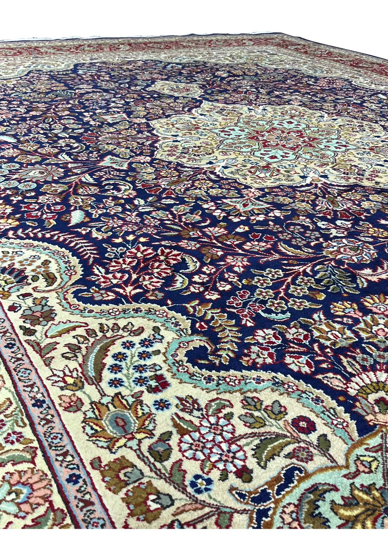 Color detail of a Persian Tabriz rug highlighting deep navy blue, ivory, burgundy red, soft gold, and pale turquoise accents