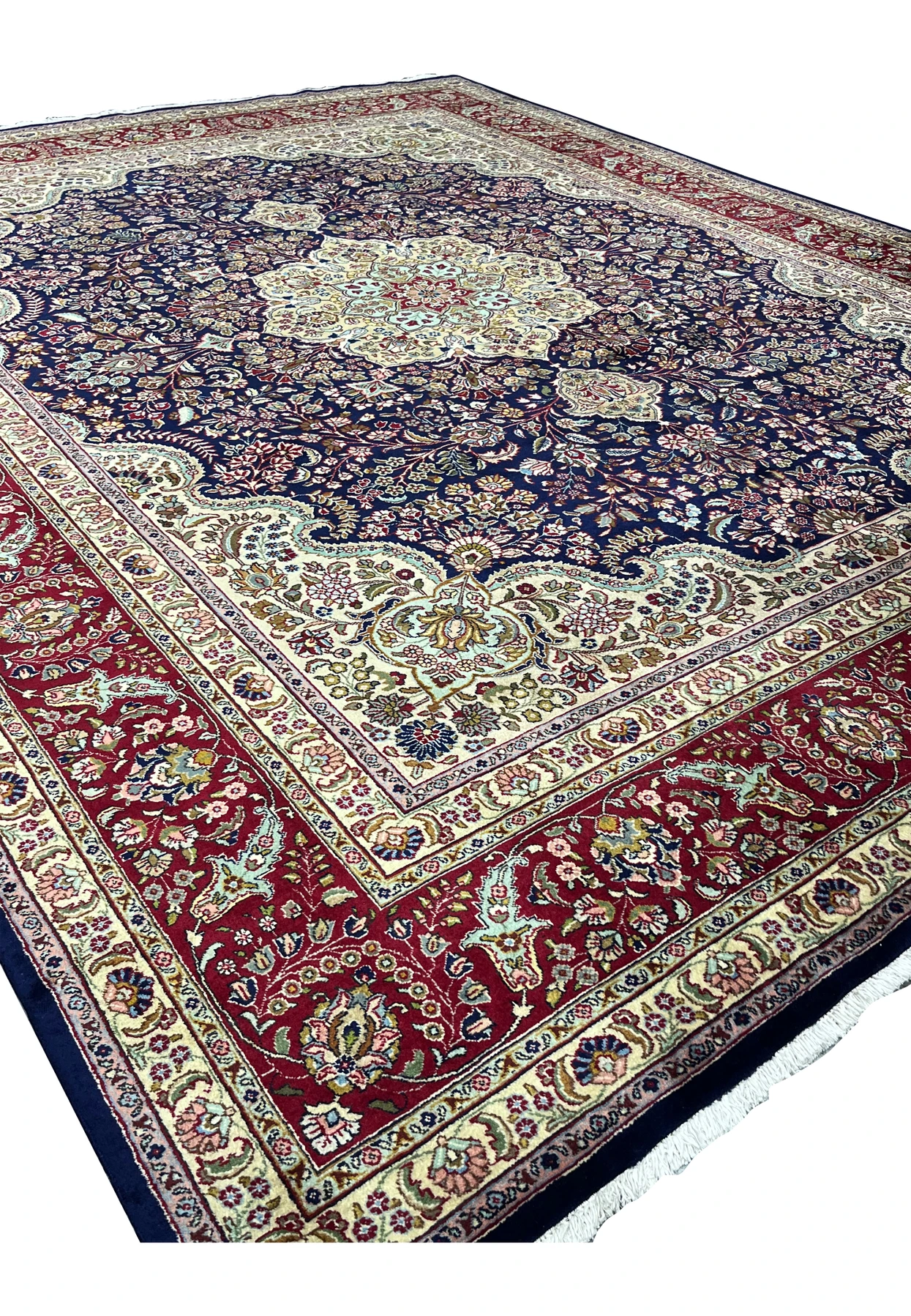 Angled view of an 11'2 x 14'4 Persian Tabriz rug with deep navy field, intricate floral vines, ivory detailing, and rich red border