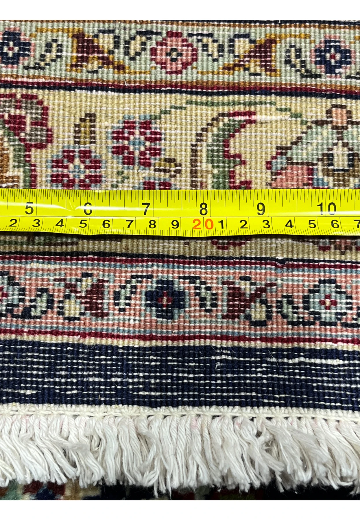 Backside of an 11'2 x 14'4 Persian Tabriz rug with ruler for scale, displaying dense hand-knotted construction and uniform weave quality