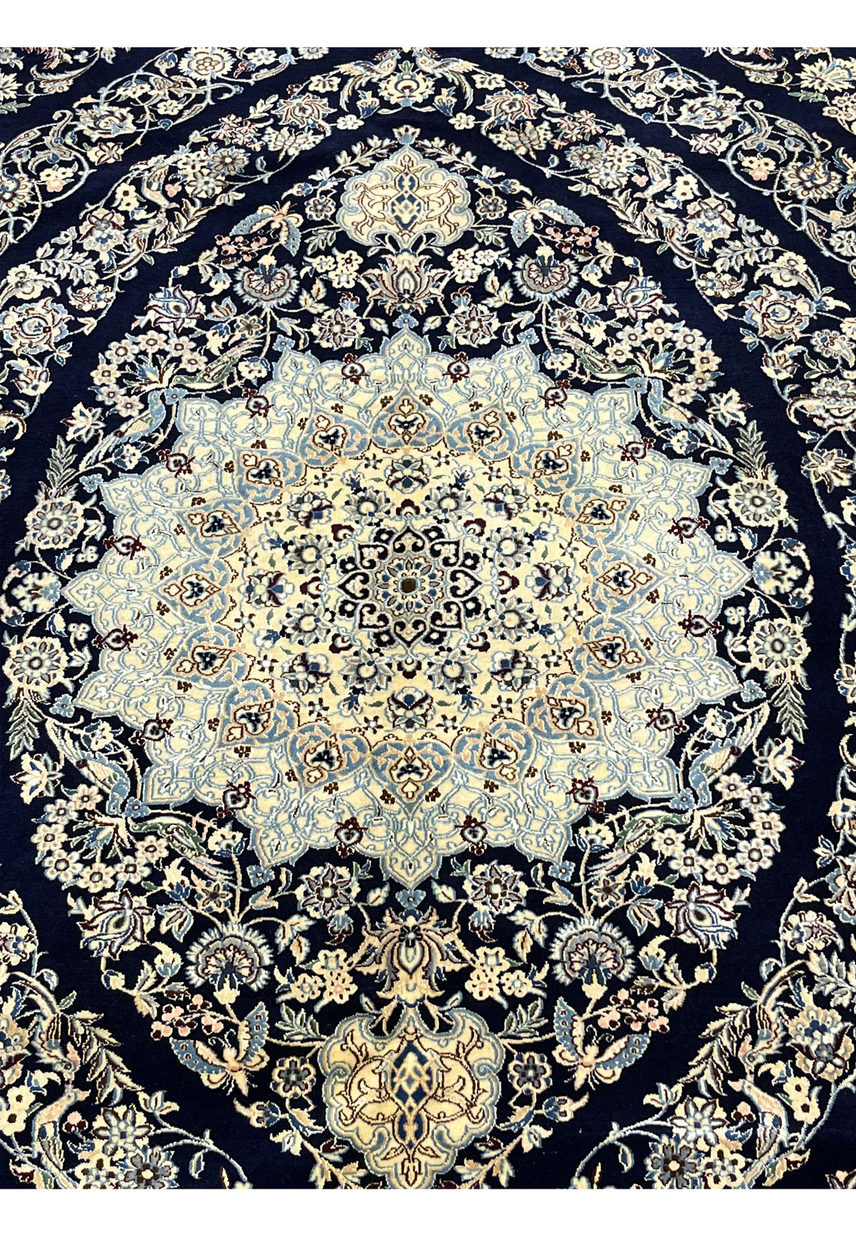 Detailed medallion of a Persian Nain 6 La rug with intricate floral motifs woven in silk and kork wool on a navy background