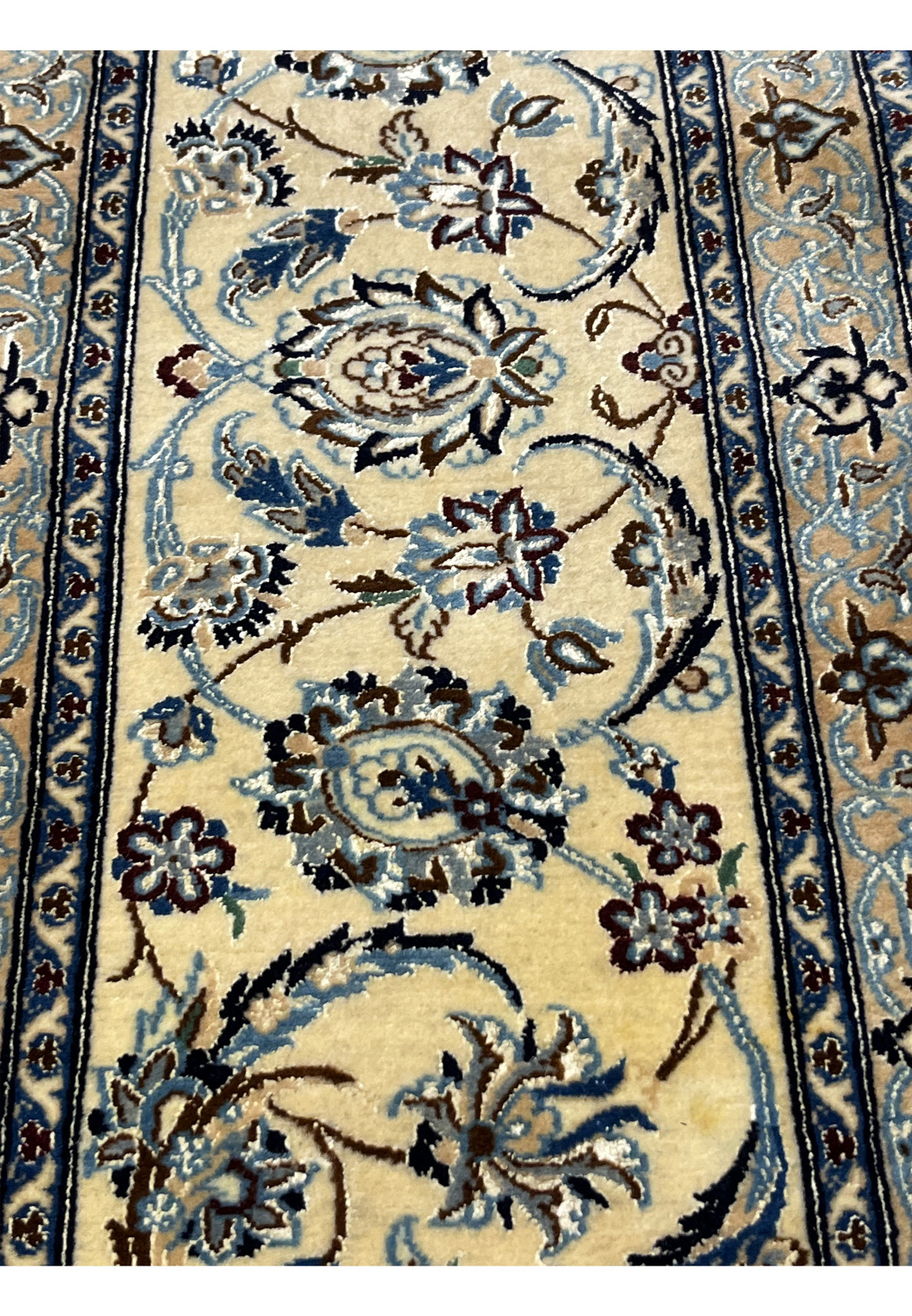 Close-up of the border on a Persian Nain 6 La rug with layered floral motifs in ivory, light blue, and navy tones