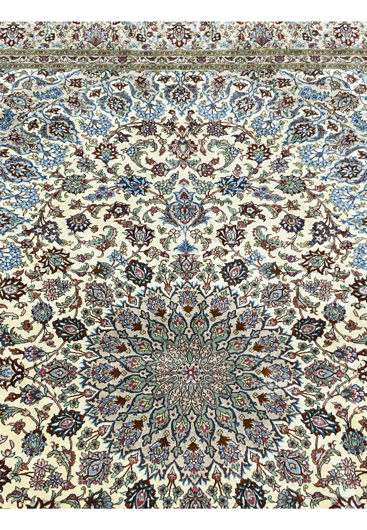 Upper section view of a signed Persian Qum pure silk rug showing refined floral motifs, symmetrical layout, and luminous silk texture against an ivory field.