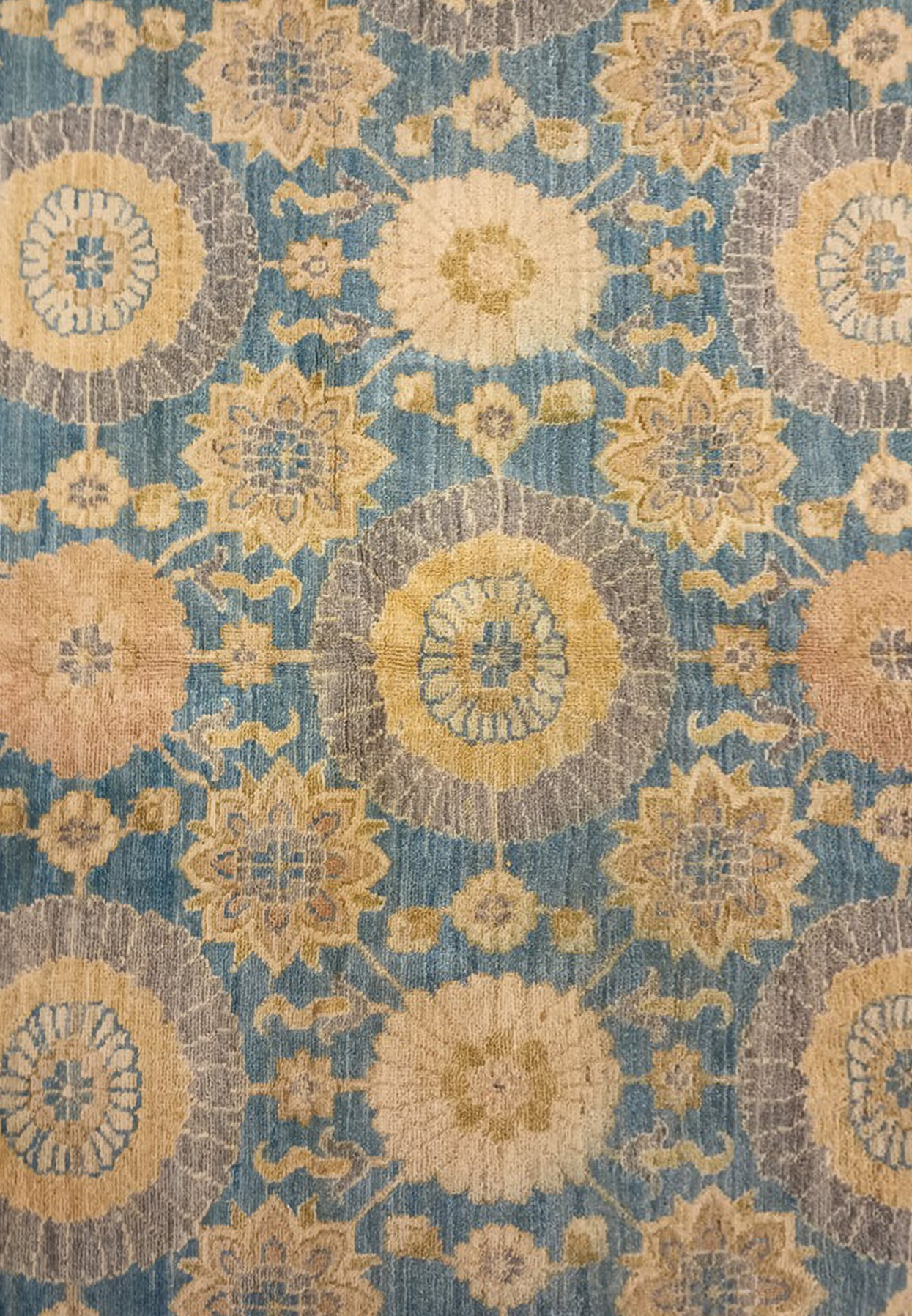 Detailed view of floral motifs on a light blue Chobi Peshawar rug with circular medallions, vine scrolls, beige, gold, and subtle grey color accents