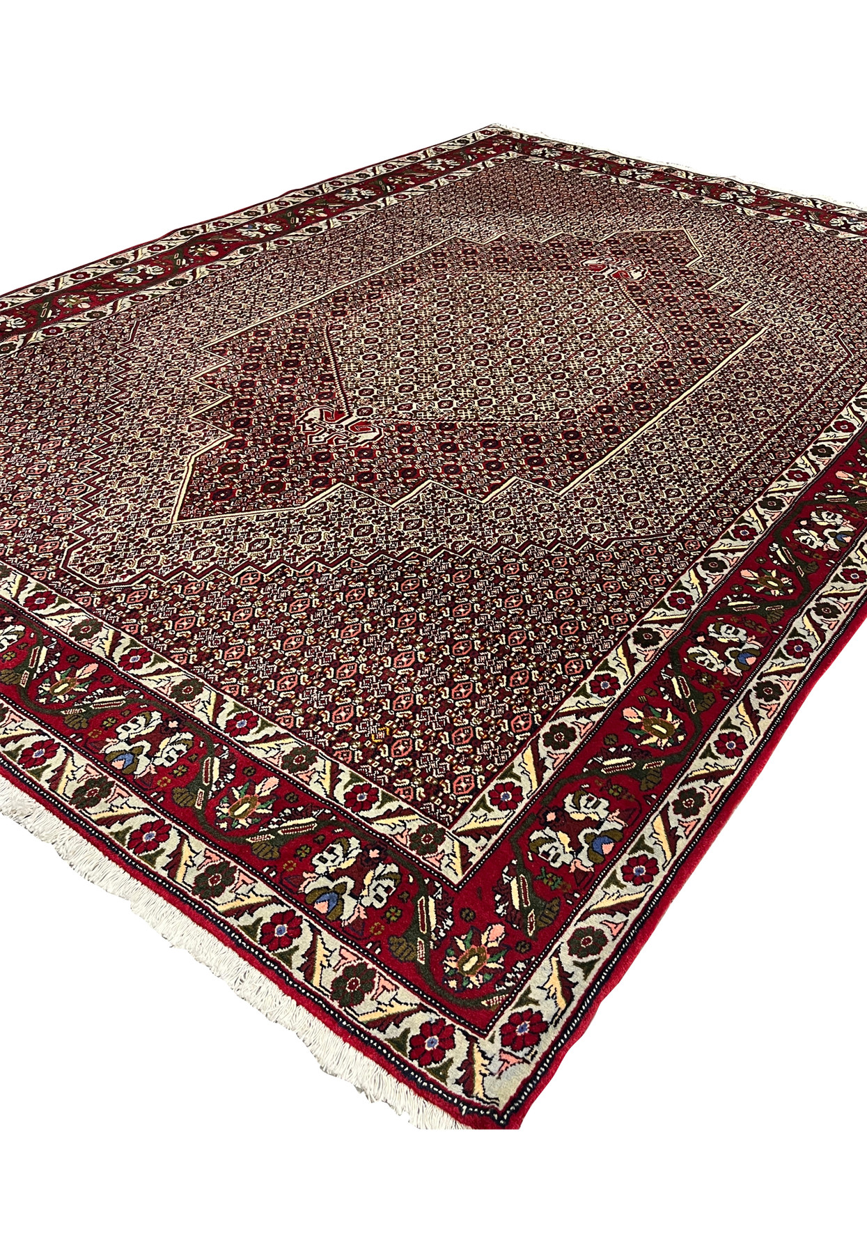Angled view of Persian Senneh rug revealing surface texture, dense knotting, stepped medallion depth, and color contrast