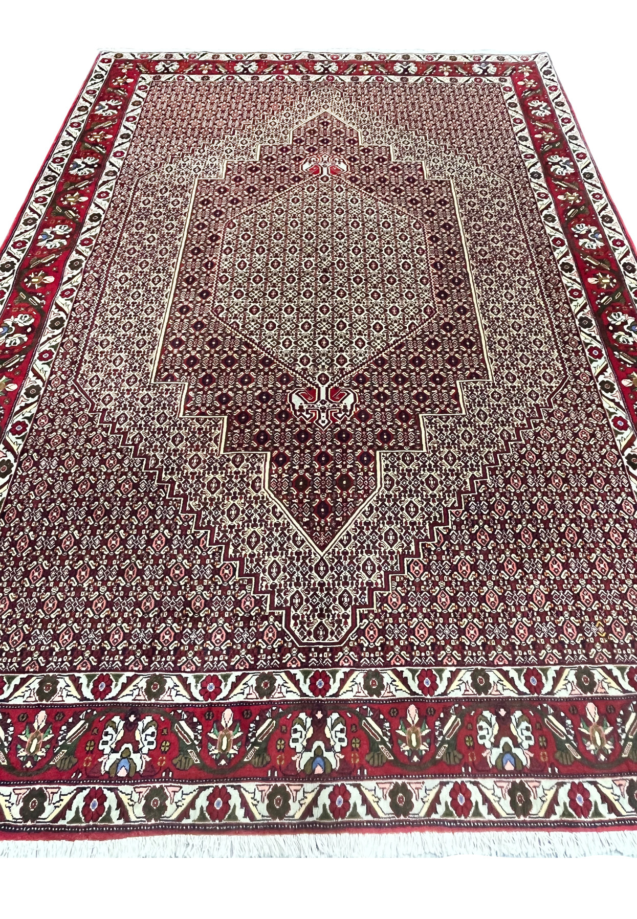 Laid flat view of Persian Senneh rug highlighting elongated medallion form, dense allover geometry, and balanced burgundy and ivory tones