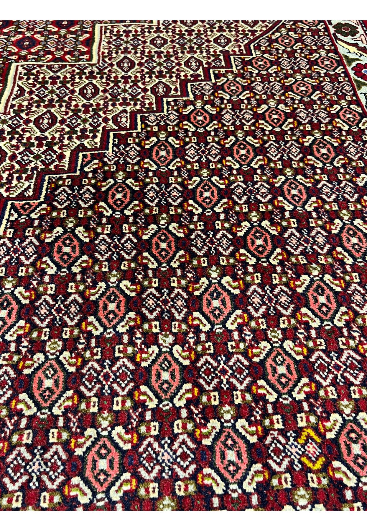 Close-up of repeating motifs in Persian Senneh rug highlighting dense geometric forms, burgundy tones, ivory contrast, and fine knot clarity