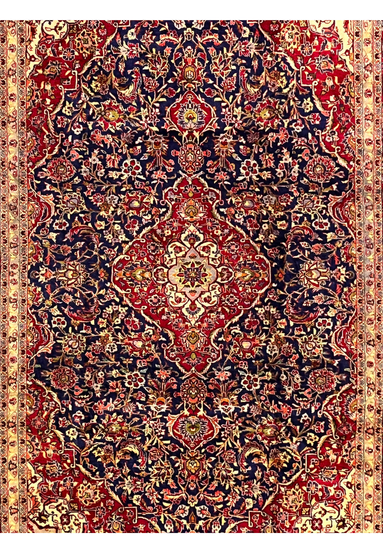 Field detail of Persian Isfahan rug featuring dense floral vines, navy blue background, soft gold accents, and fine hand knotted structure
