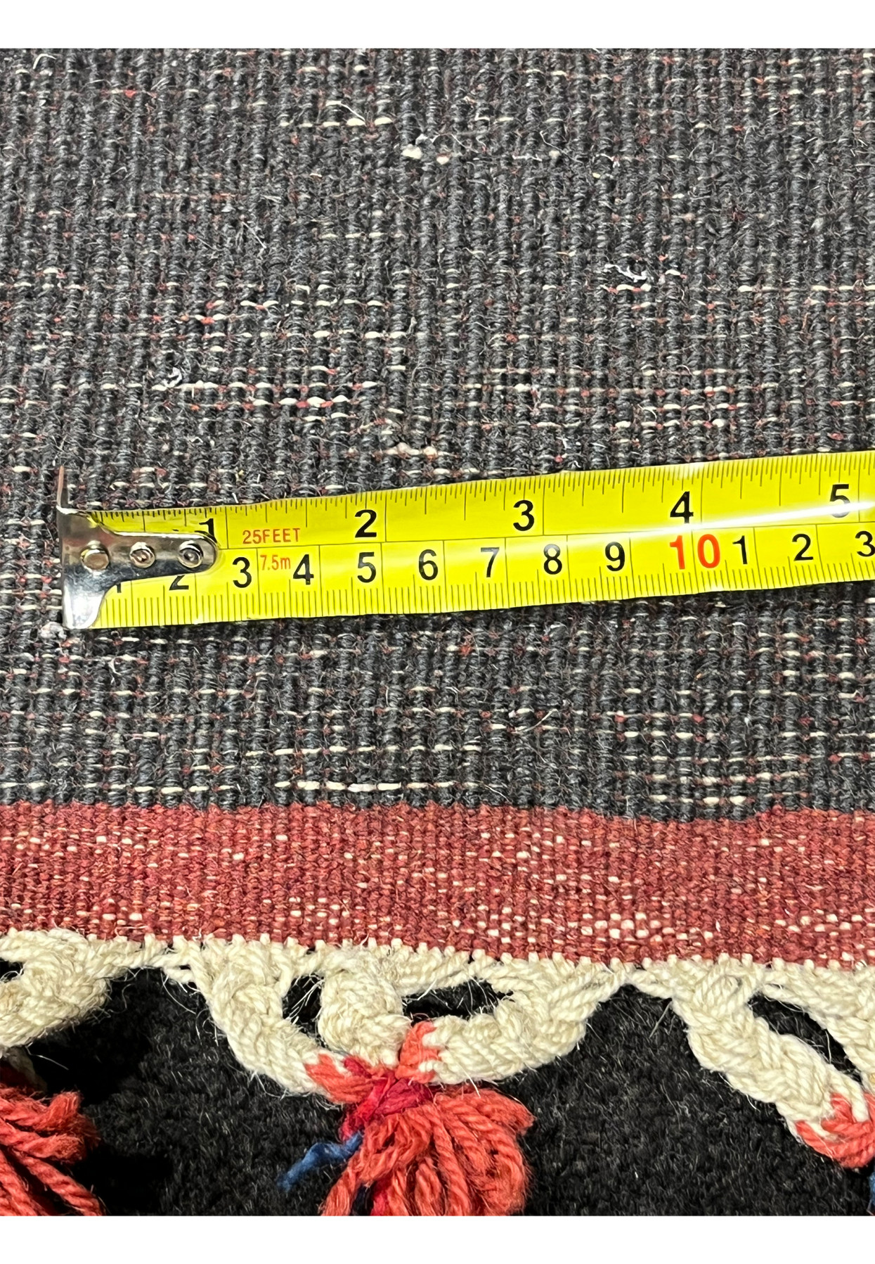 Back of Persian Gabbeh rug with measuring tape showing thickness and weave density handmade wool tribal construction with knotted fringe edge