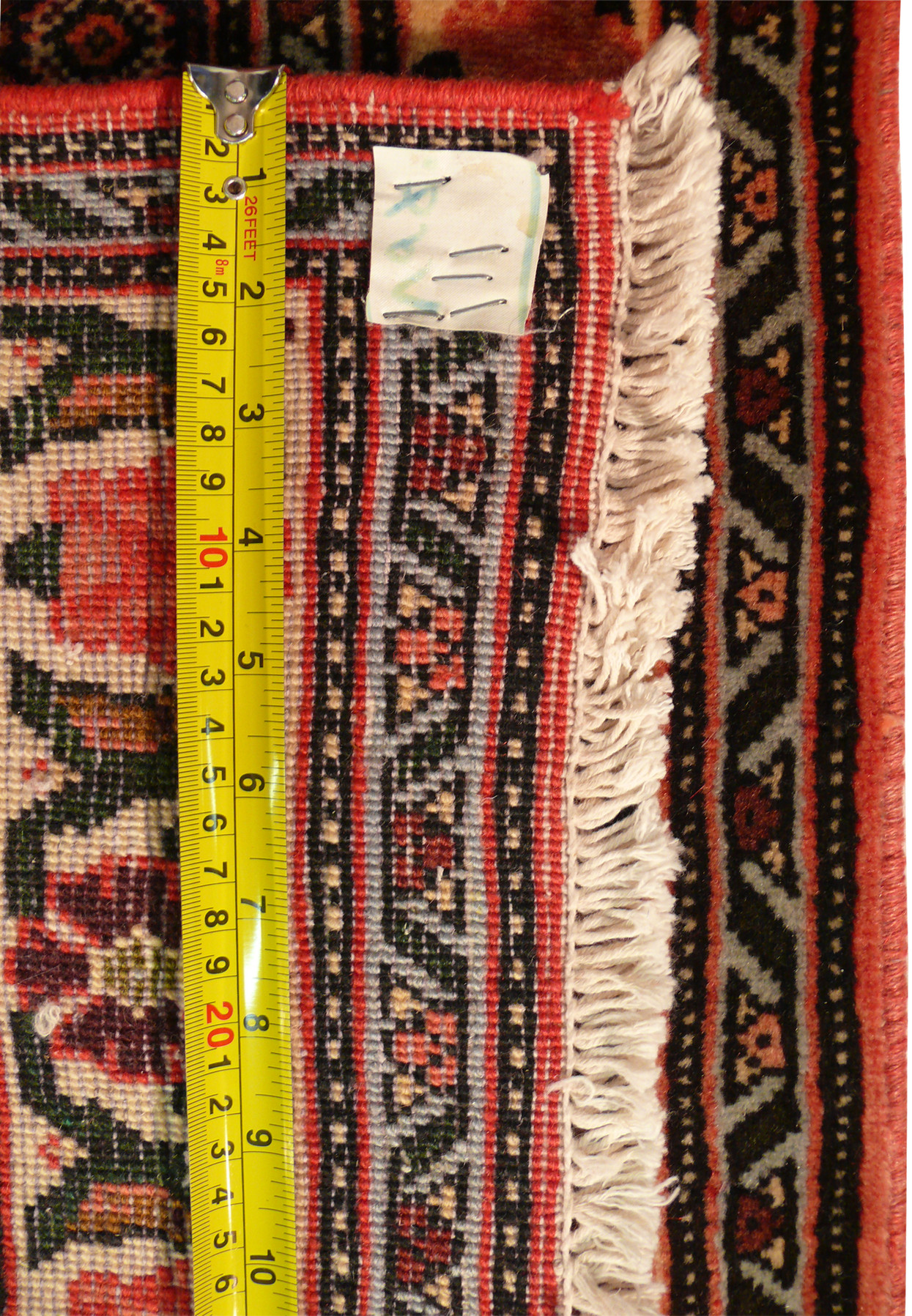 Backside weave of Persian Senneh runner showing tight knot density cotton foundation and measurement tape for scale